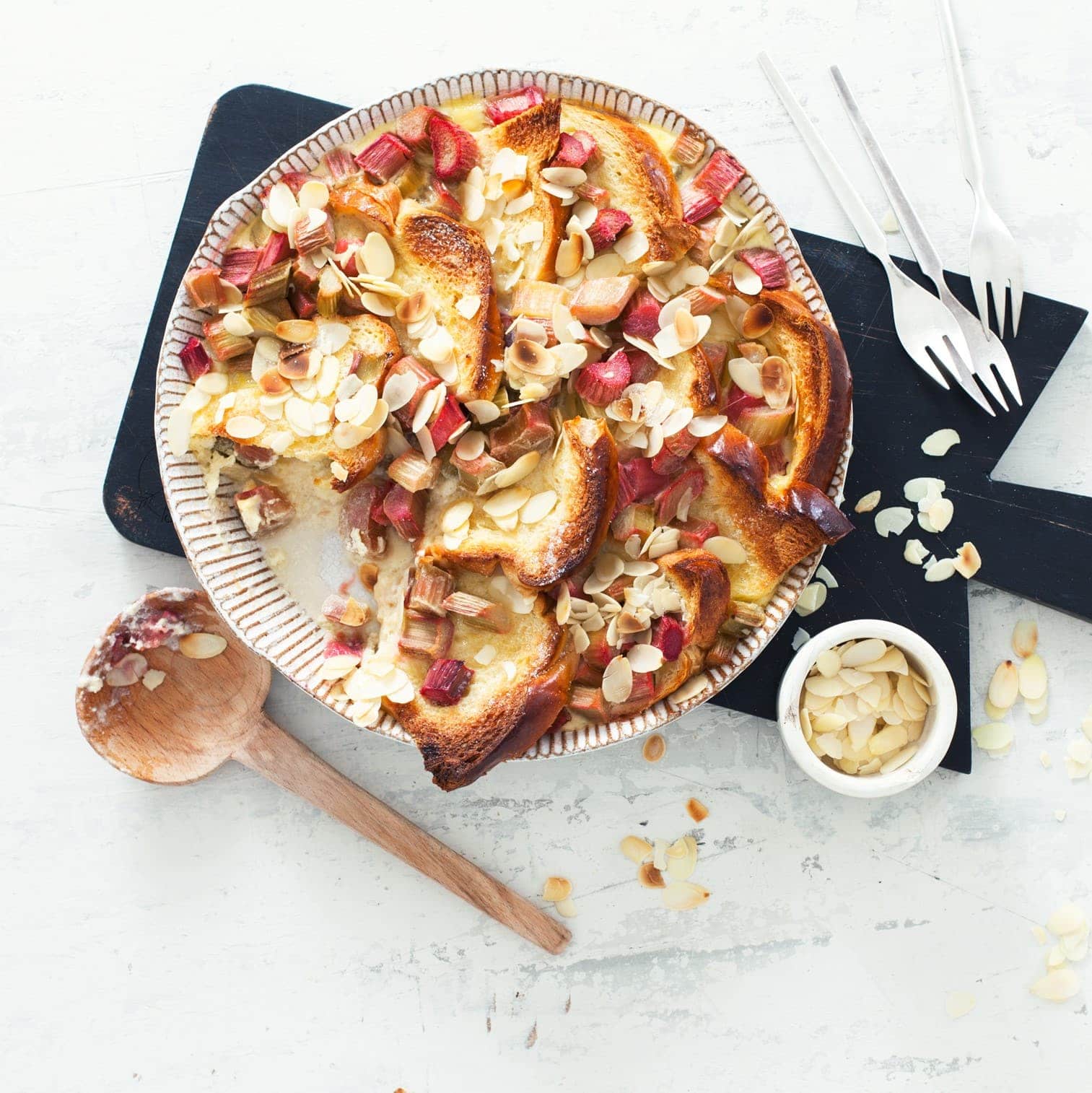 Sommerlicher Ofenschlupfer: Probieren Sie unseren süßen Brioche-Auflauf mit frischem Rhabarber und Mandelblättchen - als Hauptspeise oder Dessert!