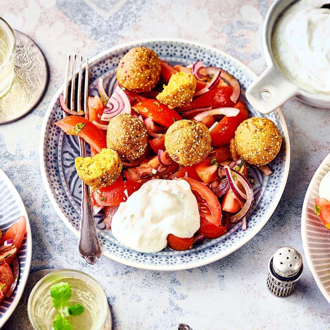 Genießen wie im Orient: Probieren Sie unsere Falafel aus Hirse und Kichererbsen mit Kräuter-Joghurt-Quark, dazu einen Tomaten-Zwiebel-Minze-Salat an Balsamico-Dressing – fertig in 25 Minuten!