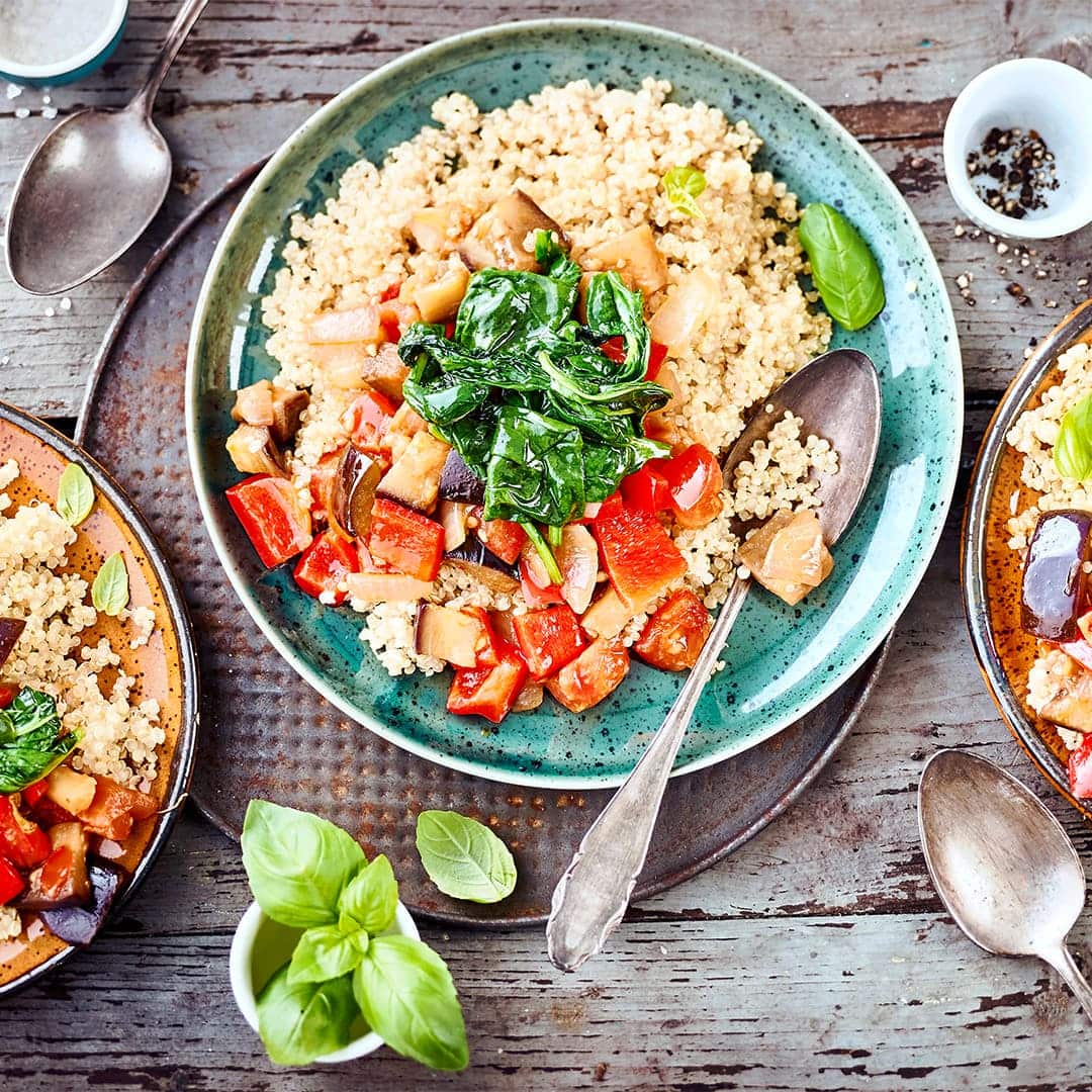 Quinoa-Ratatouille: Probieren Sie unser veganes Gericht mit Auberginen-Paprikagemüse, Babyspinat und Tomaten, gewürzt mit Knoblauch und Basilikum!
