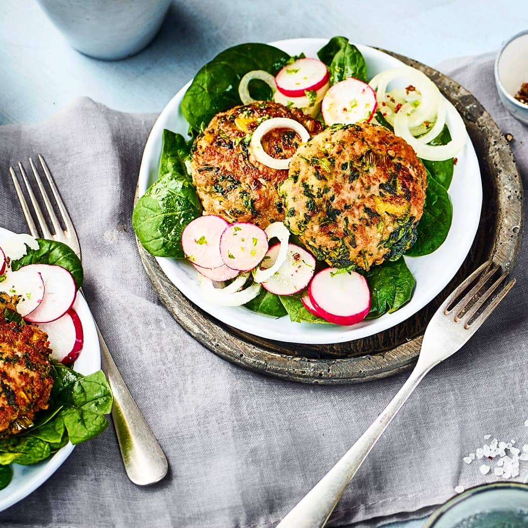 Frikadellen mal anders: Unser Rezept für Frikadellen mit Spinat und Frühlingszwiebeln wird mit einem Salat aus jungen Spinat und Radieschen serviert.