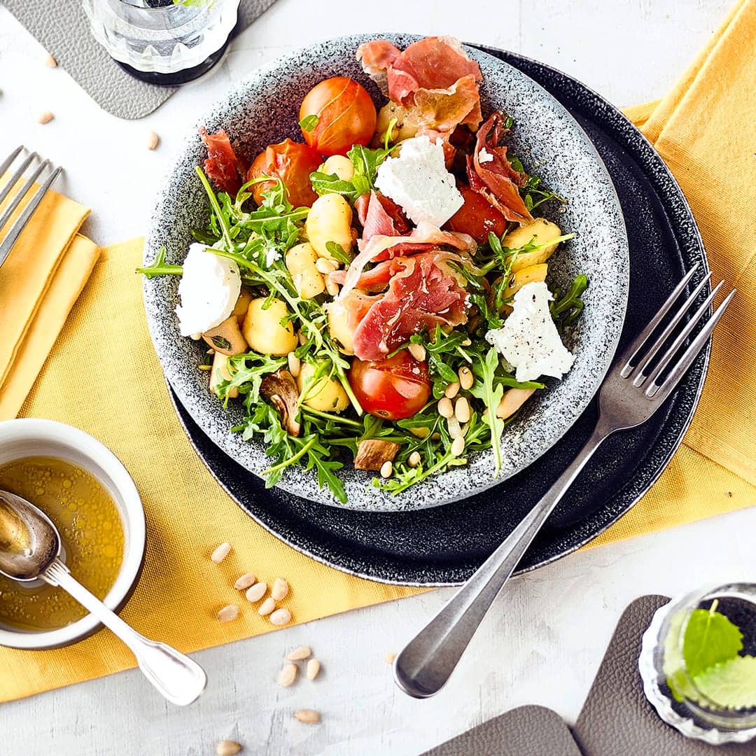 Ein Salat mit leckerem und sättigendem Inhalt: Unser Rezept für einen Gnocchi-Salat mit frischen Gnocchi, Kräuterseitlingen, Serrano-Schinken, Rucola und Ziegenkäse. Dazu passt eine Honig-Vinaigrette.