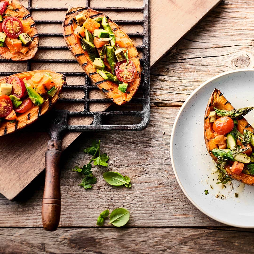 Eine fantastische Beilage, die Sie so vielleicht noch nicht probiert haben: Süßkartoffel vom Grill mit Tomaten-Avocado-Spargel-Topping und selbstgemachter Kräutersoße.