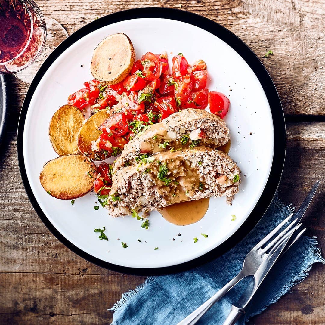 Kann es mit jedem Festtagsmenü aufnehmen: Ein würziger Braten aus gemischtem Hackfleisch mit fein gewürfelten Äpfeln. Dazu Kartoffeln und fein geschmorte Tomaten.