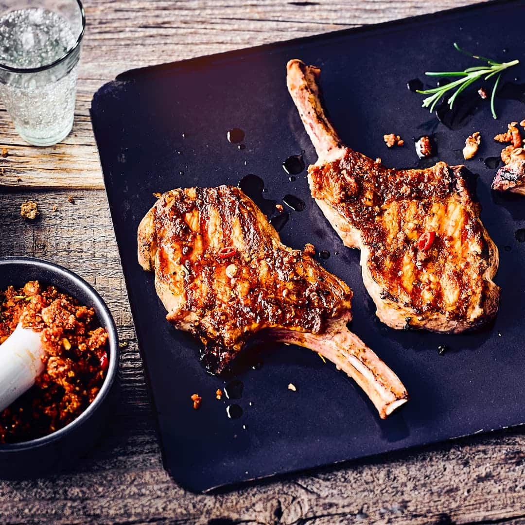 Saftiges Iberico-Kotelett vom Grill mit einem fruchtigen Rub mit Orange, Haselnüssen, Rosmarin und Knoblauch. Das Fleisch ist herrlich saftig und die Kruste schön kross.