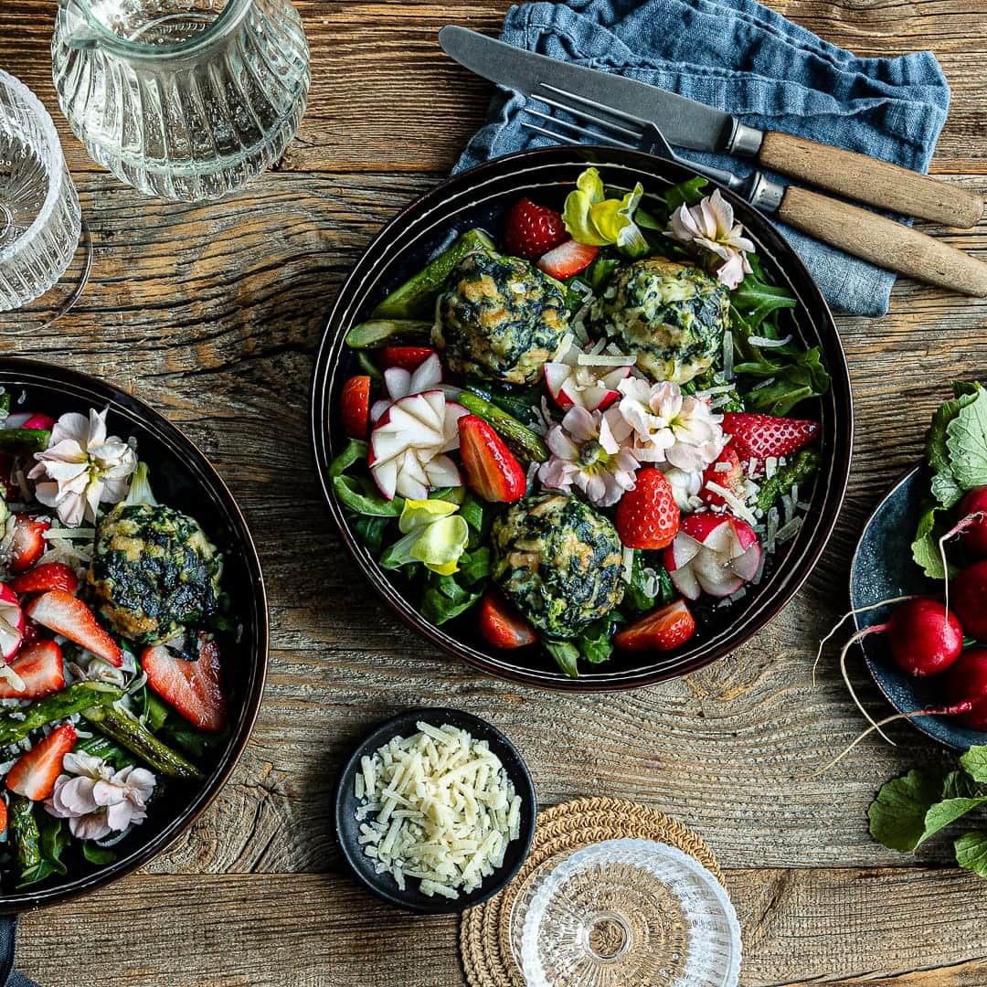 Jetzt gibt’s Frühling auf den Teller: Würzige Ricotta-Spinat-Knödel mit Frühlingssalat aus Spargel, Rucola, Erdbeeren und Parmesan.