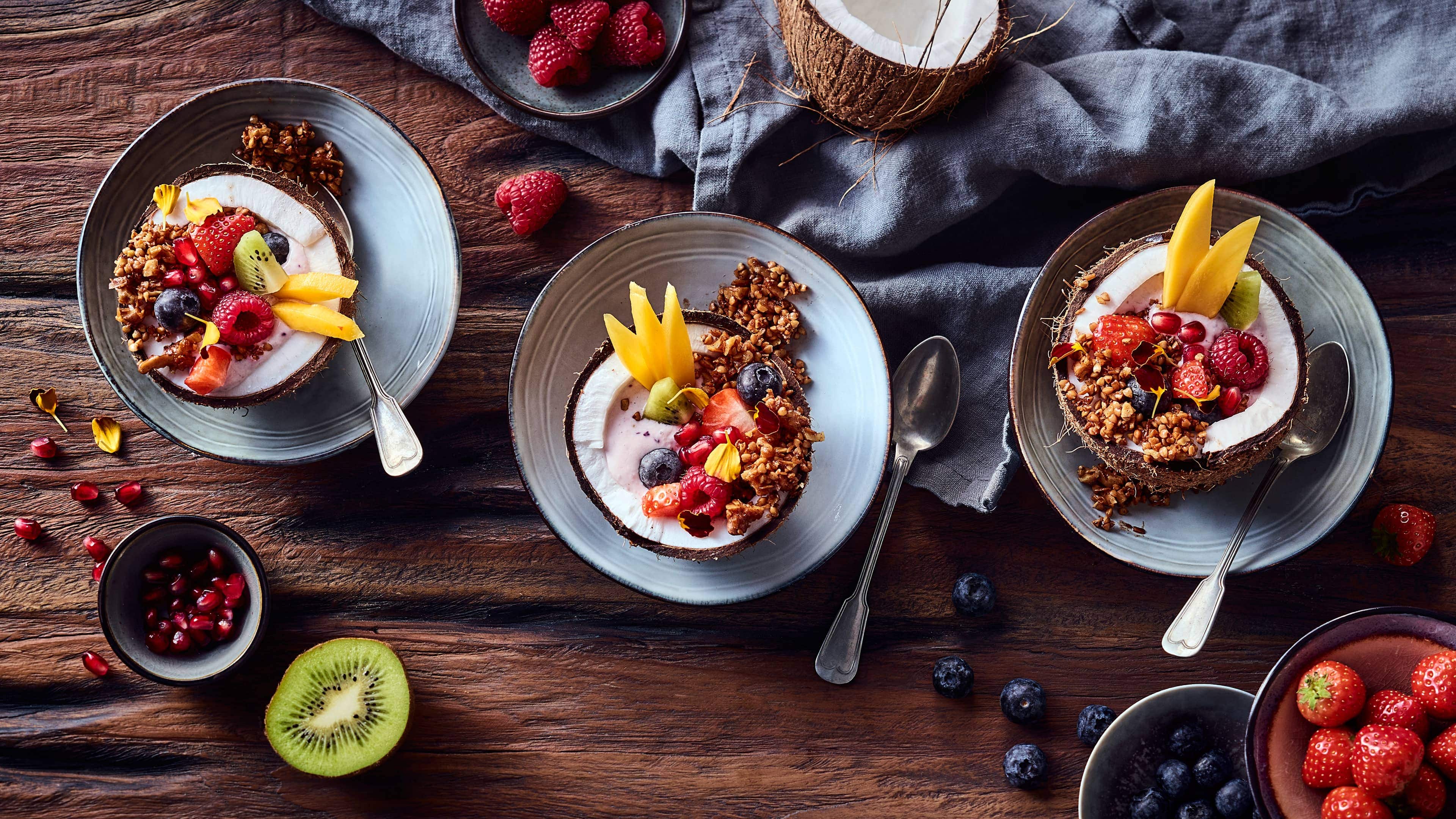 Coconut Bowl Fruchtige Frühstücks Bowl mit knusprigem Buchweizen-Granola, angerichtet in Kokosnusshälften.