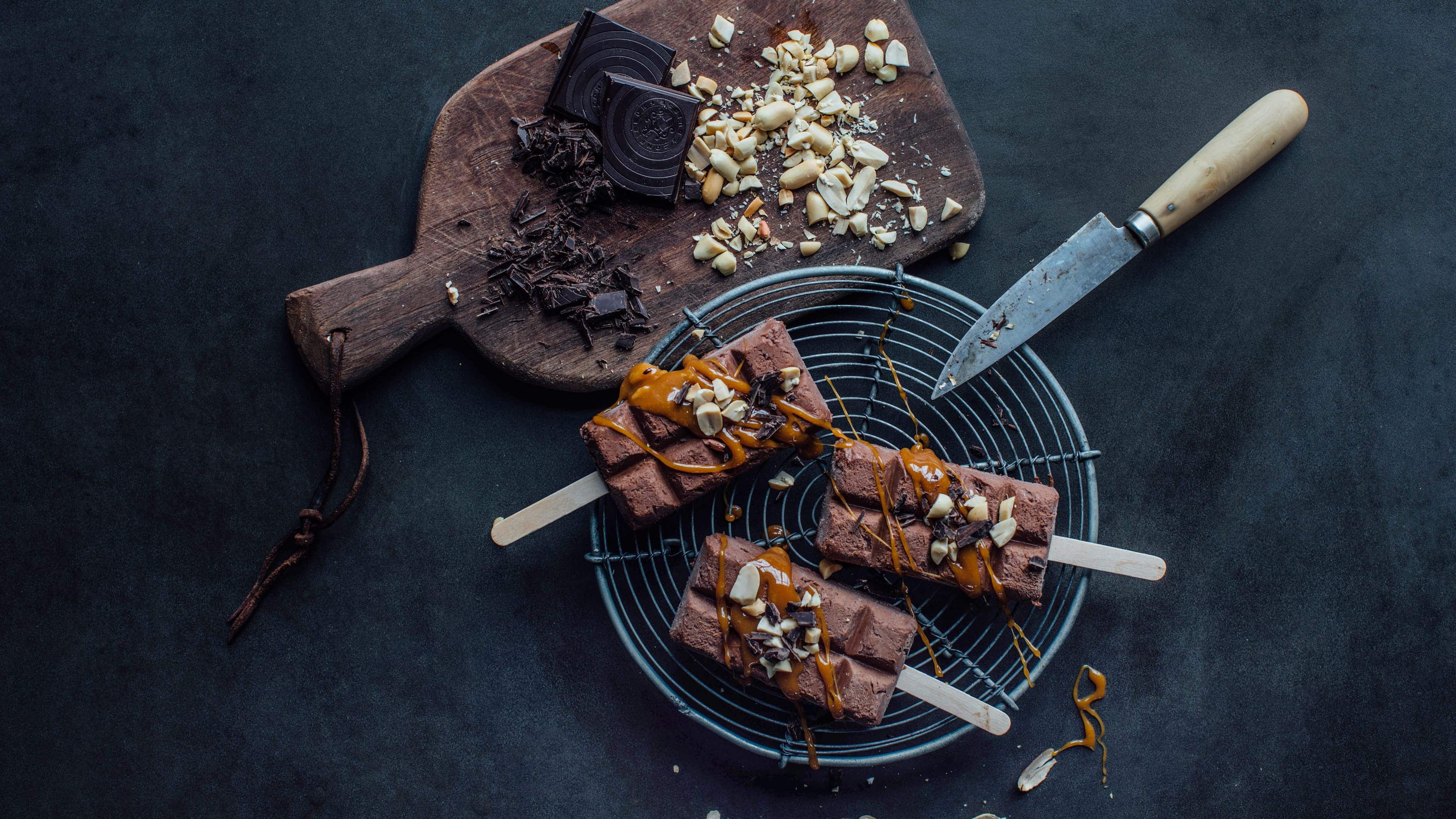 Schokoladen-Eis-Pops Ein Schokoladen-Eis-Traum erwartet Sie bei unserem Rezept für selbstgemachte Schokoladen-Eis-Pops mit Karamellsauce und gehackten Erdnüssen.