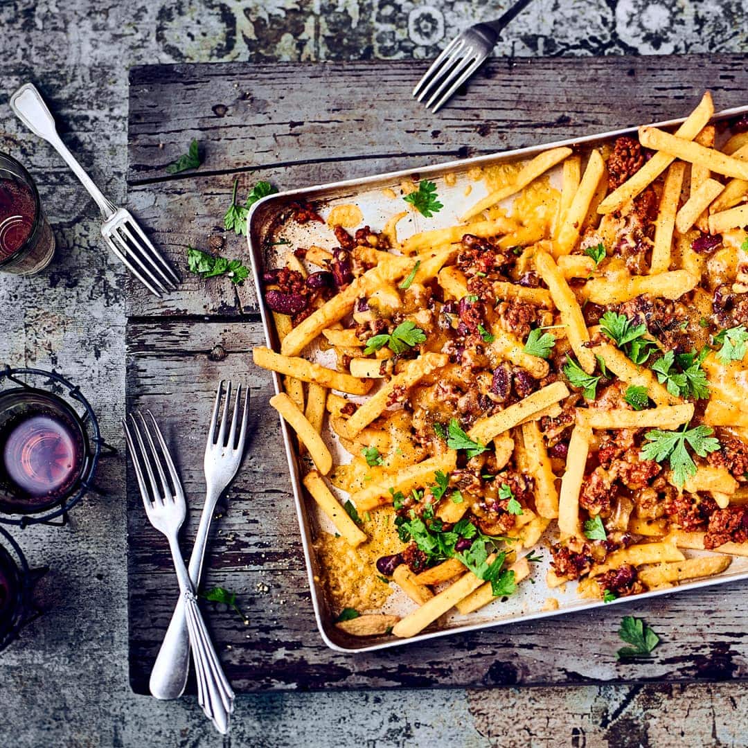 Vorsicht, heiß und extrem lecker! Frisch aus dem Ofen kommen die Chili Cheese Fries: Selbstgemachte Pommes mit Chili con Carne und Cheddar überbacken!
