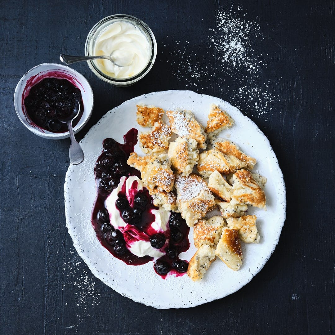 Die beliebte Mehlspeise lässt sich vielseitig versüßen - wir verfeinern unseren Kaiserschmarrn mit Mohn und servieren ihn mit Heidelbeeren und Crème fraîche.