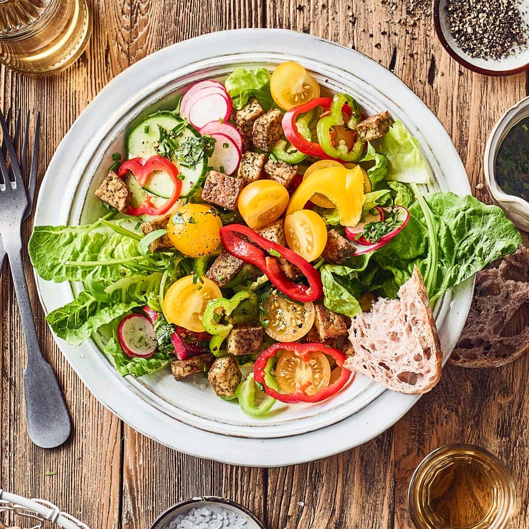 Knackig frische Salatherzen mit Mini-Paprika, Kirschtomaten, Salatgurke, Radieschen und Rucola, als Topping gebratener Kräuter-Tofu.