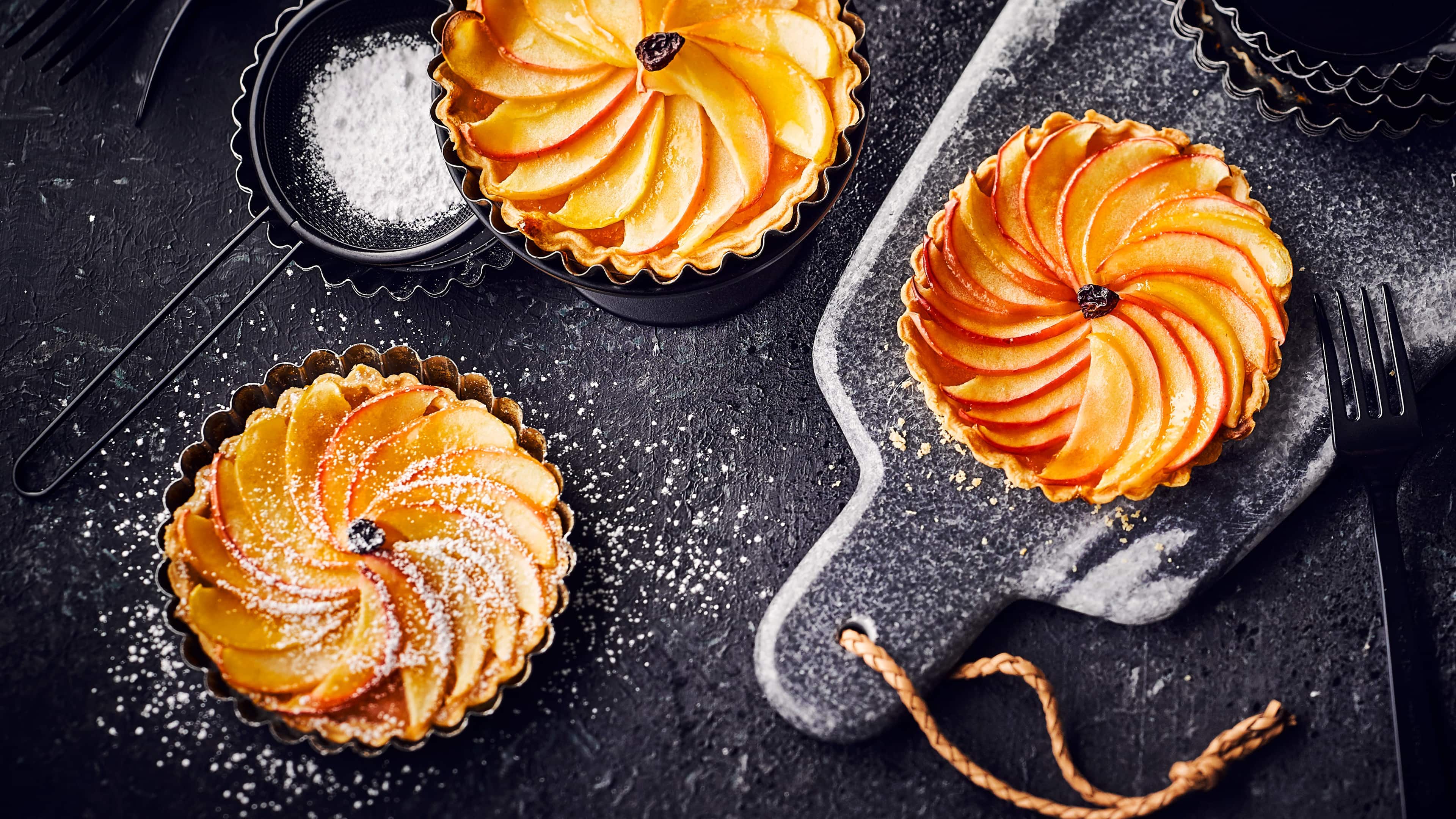 Apfeltartelettes Verzaubern Sie Ihre Gäste mit diesem fruchtig-frischen Dessert: Probieren Sie unser Rezept für kleine Apfeltartelettes mit Aprikosenkonfitüre und Korinthen aus – süß und lecker!