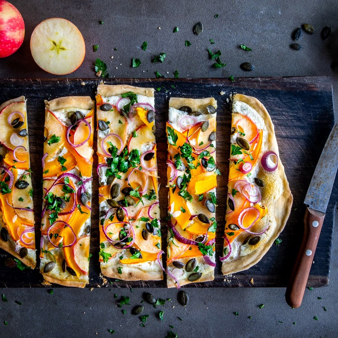 Entdecken Sie dieses edle Rezept für die kulinarischen Herbstmomente: Ein hauchdünner Fladen wird köstlich belegt mit fruchtigem Kürbis, aromatischem Ziegenfrischkäse, knackigen Äpfeln und leckeren Kürbiskernen!