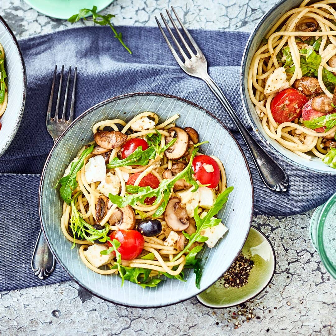Unser Rezept für Spaghettisalat mit Rucola ist in nur 15 Minuten zubereitet: Mit Champignons, Büffelmozzarella, Kirschtomaten und Oliven – gleich ausprobieren!