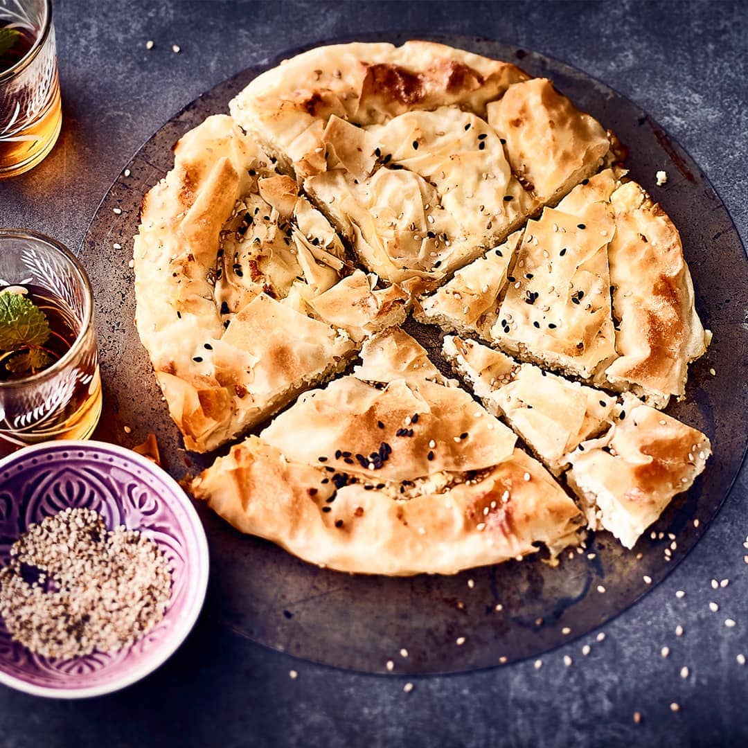 Blatt für Blatt wird der Yufka-Teig geschichtet, bepinselt und nach und nach mit Feta-Käse bestreut. So entsteht leckerer Burek mit Käse.