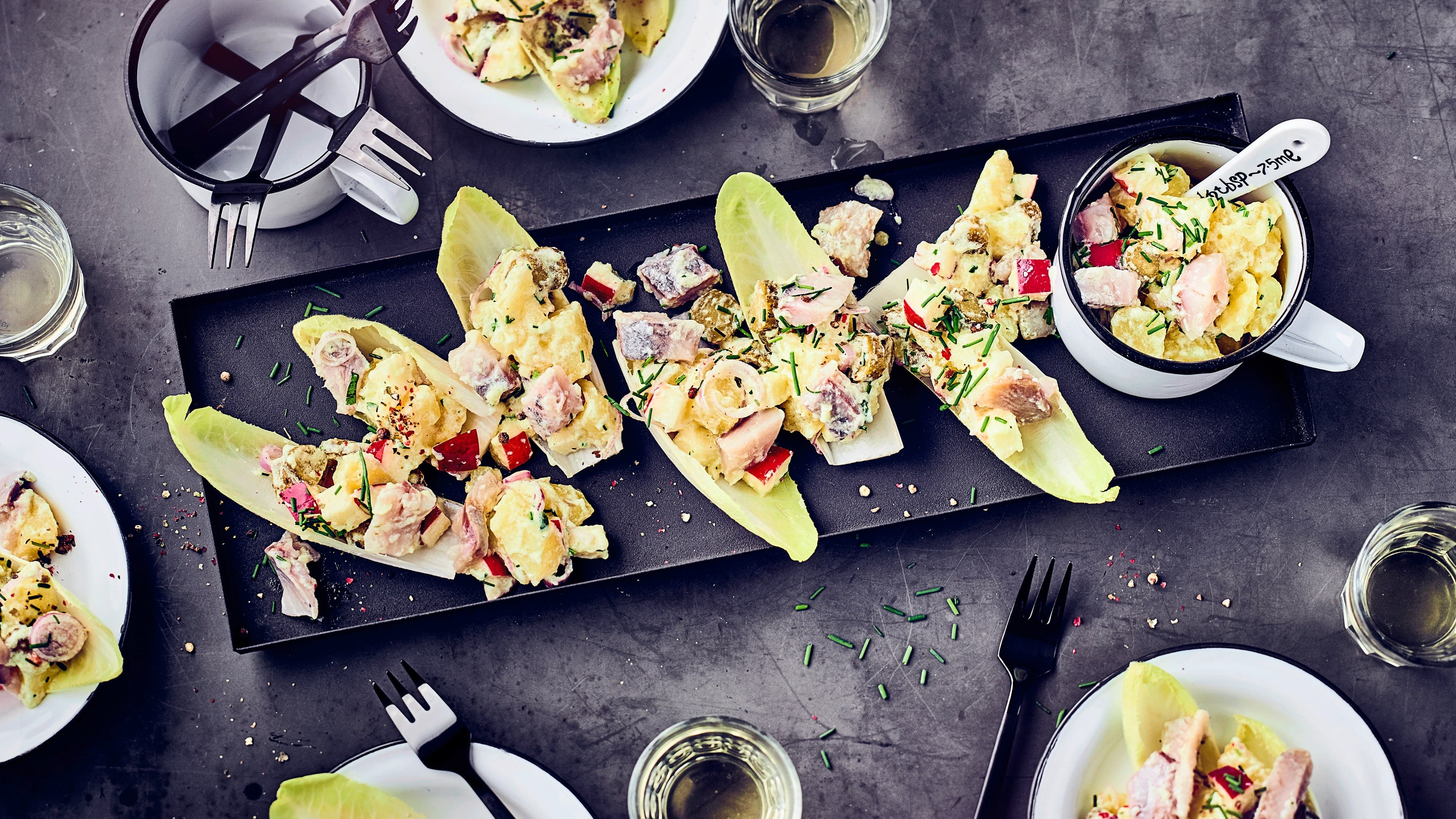 Kartoffelsalat mit Matjes Kartoffelsalat mit Matjes, Gurke und Apfel, im Chicoreeblatt serviert.