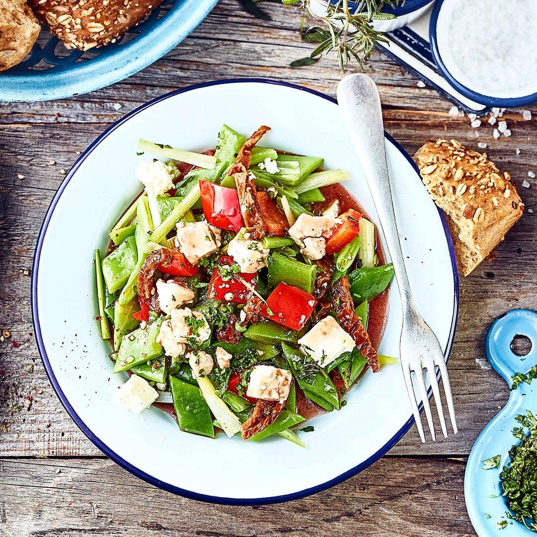 Vegetarisches Gericht aus der mediterranen Küche: Genießen Sie unseren Salat mit Stangenbohnen und Paprika, getrockneten Tomaten, Knoblauch und Schafskäse.