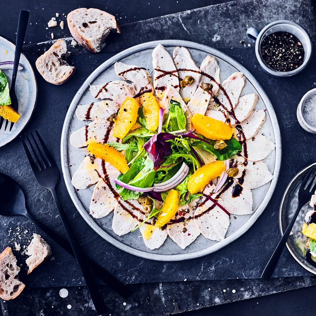 Carpaccio, muss nicht immer mit rohem Rindfleisch zubereitet werden. Wir bereiten die italienische Vorspeise mit Putenbrust und Orangen zu, die ganz fein geschnitten werden. Kapern und Zwiebeln runden das Putenbrust-Carpaccio perfekt ab.