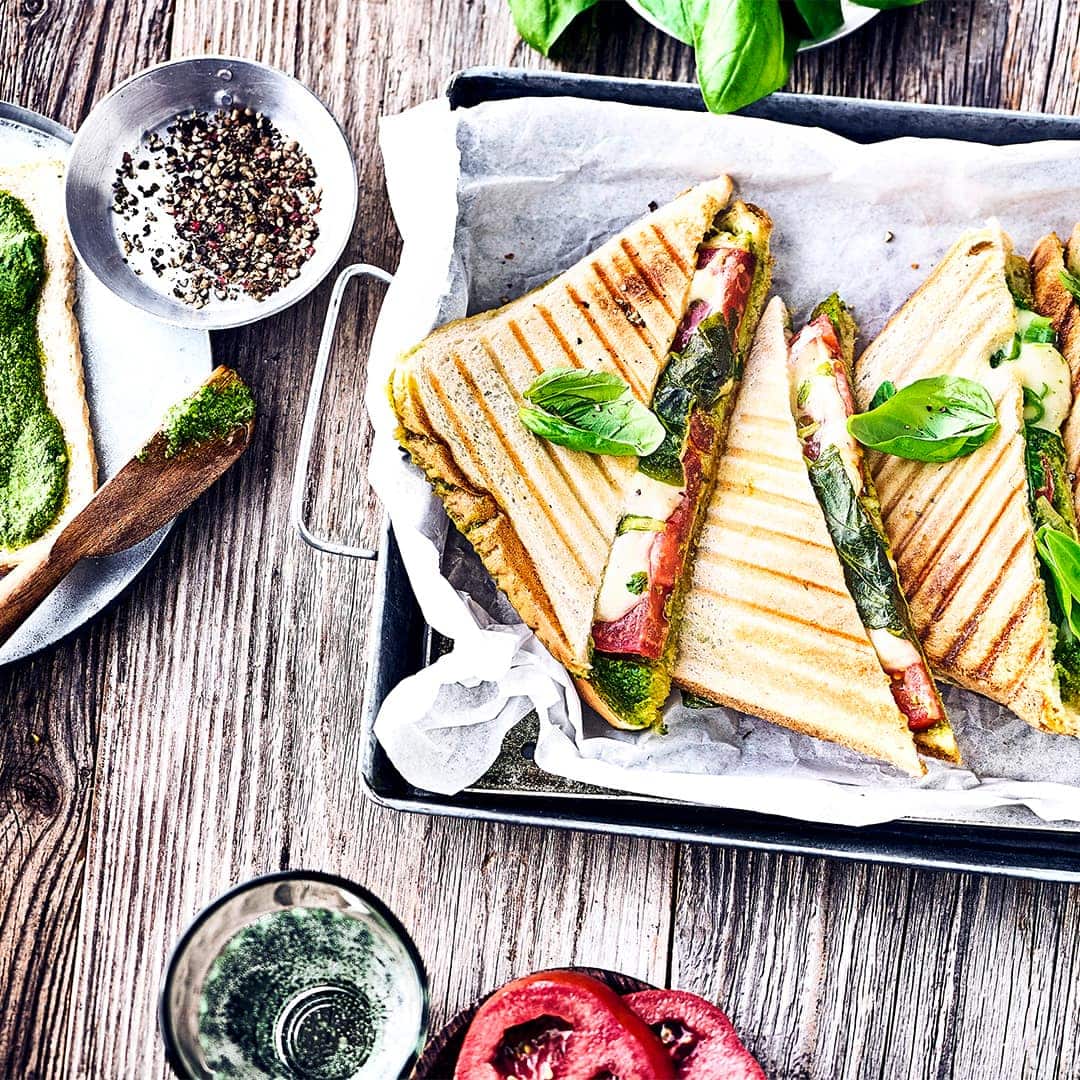Ruck-Zuck ab in den Sandwichmaker und direkt genießen. Das gegrillte Tomate-Mozzarella-Toast mit selbstgemachtem grünem Pesto ist unsere besonders leckere Variante der leckeren Sandwiches.