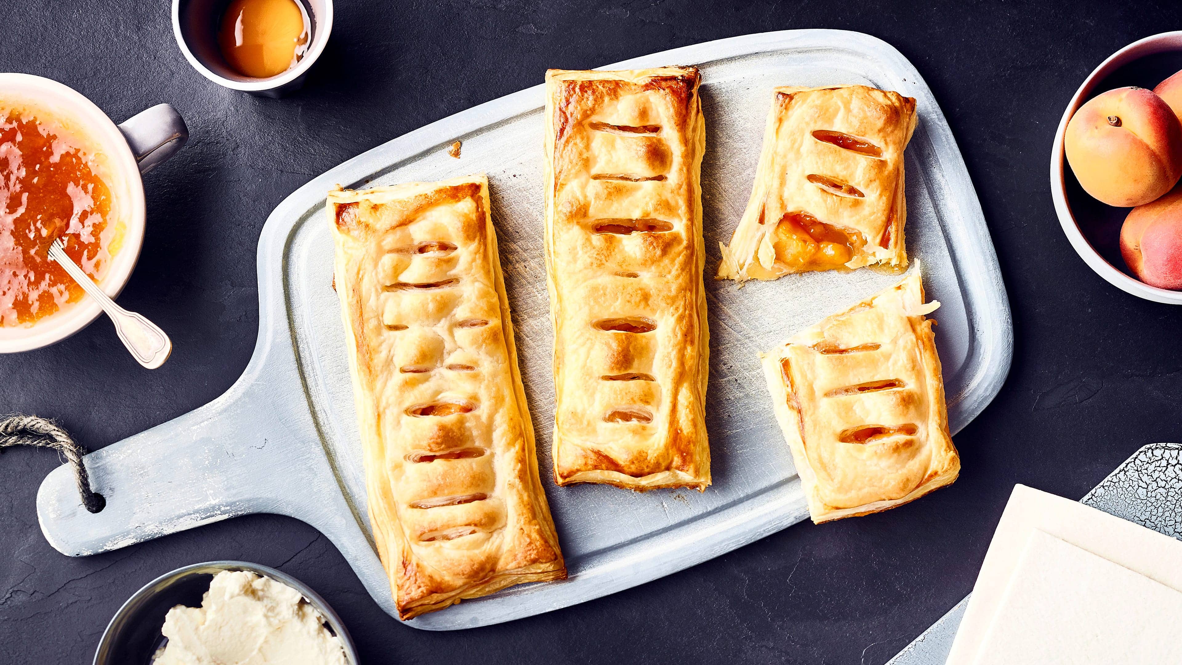 Aprikosen-Blätterteigtaschen Ein köstliches Süßgebäck und ganz einfach selbergemacht: Blätterteigröllchen mit Aprikosen und Sommerfruchtfüllung. Dazu frische Schlagsahne.