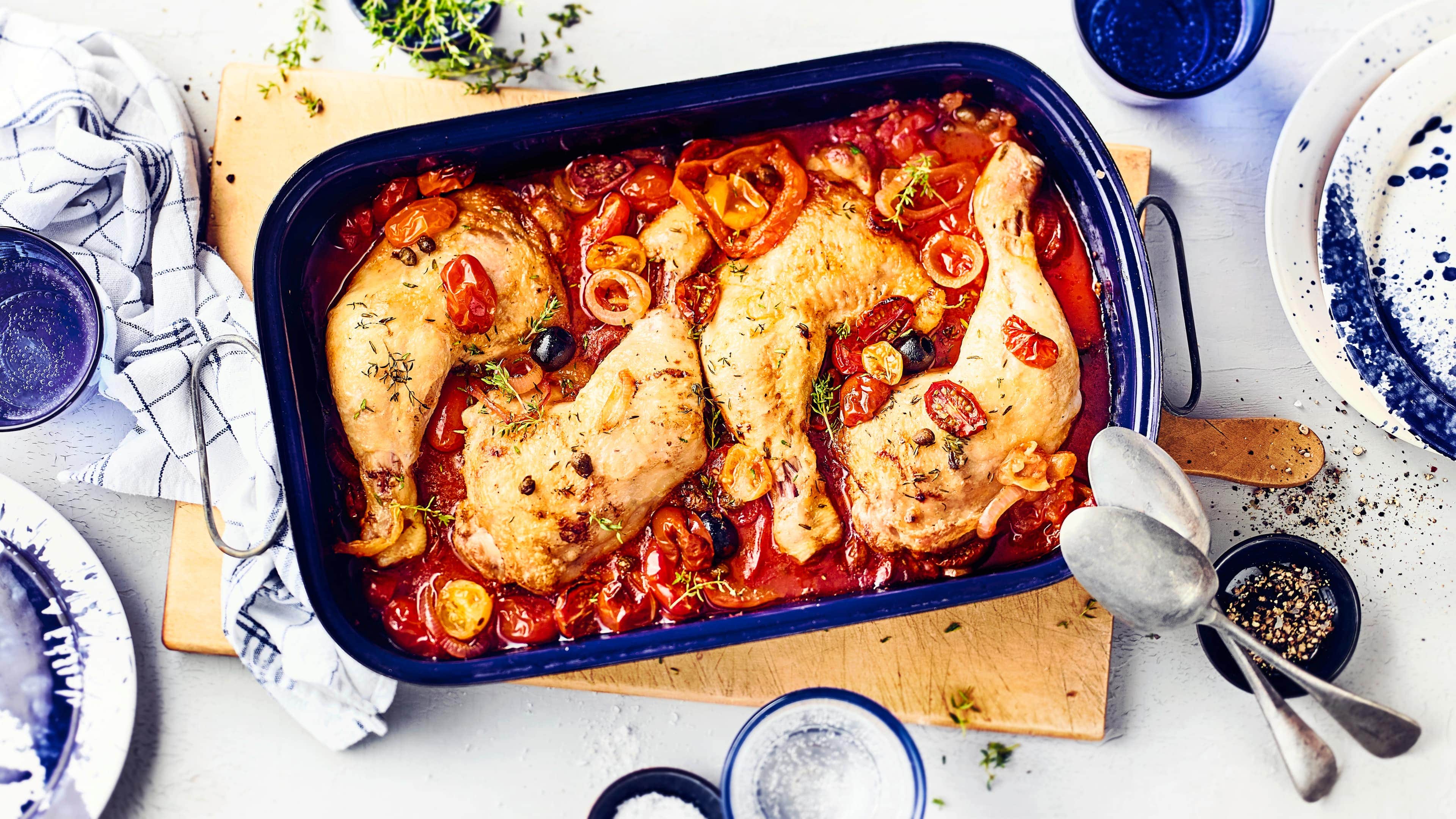 Geschmorte Hähnchenkeulen Mediterranes Geflügelgericht aus dem Ofen für Feinschmecker: Probieren Sie unsere geschmorten Hähnchenkeulen mit verschiedenen Tomatensorten, Kapern und schwarzen Oliven!
