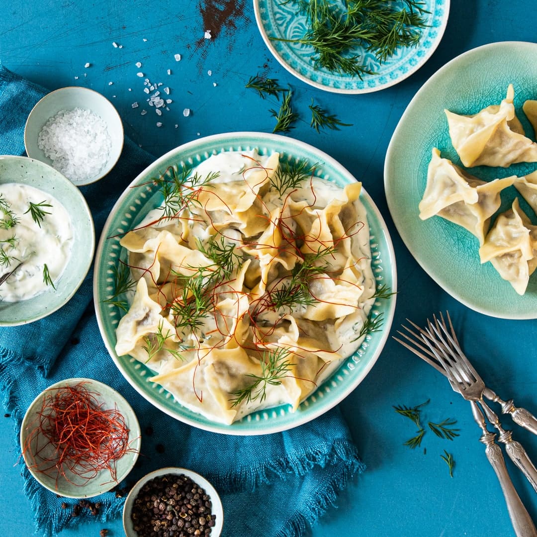 Manti sind kleine mit Hackfleisch, Speck und Zwiebeln gefüllte Teigtaschen, die mit leckerer Soße aus Dill und Crème fraîche gereicht werden.