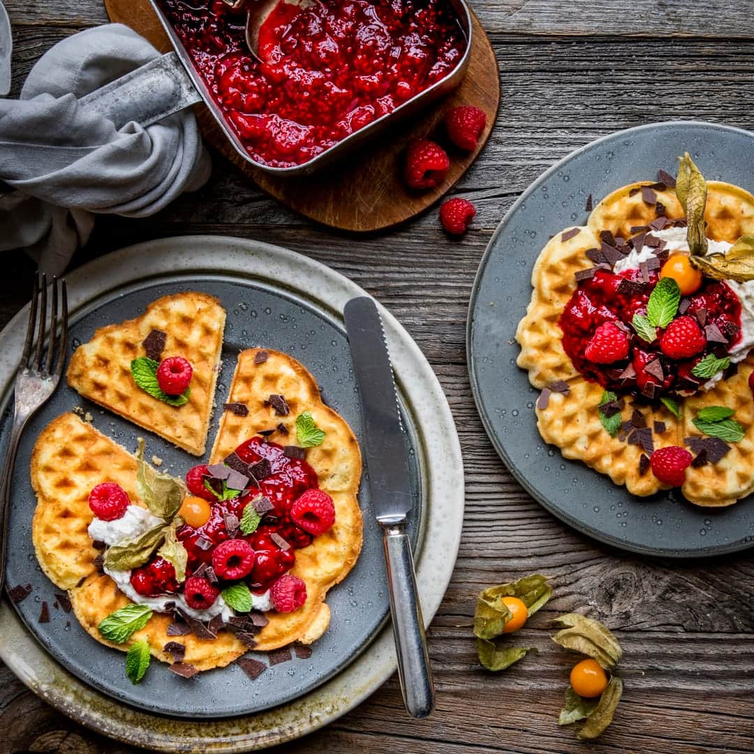 Es ist Waffelzeit! Herrlich nach warmer Butter und Zucker duftend und mit einem Topping aus Himbeerkompott und Mascarponecreme kombiniert werden unsere Waffeln anschließend noch mit frischen Früchten und Schokoraspeln garniert serviert!