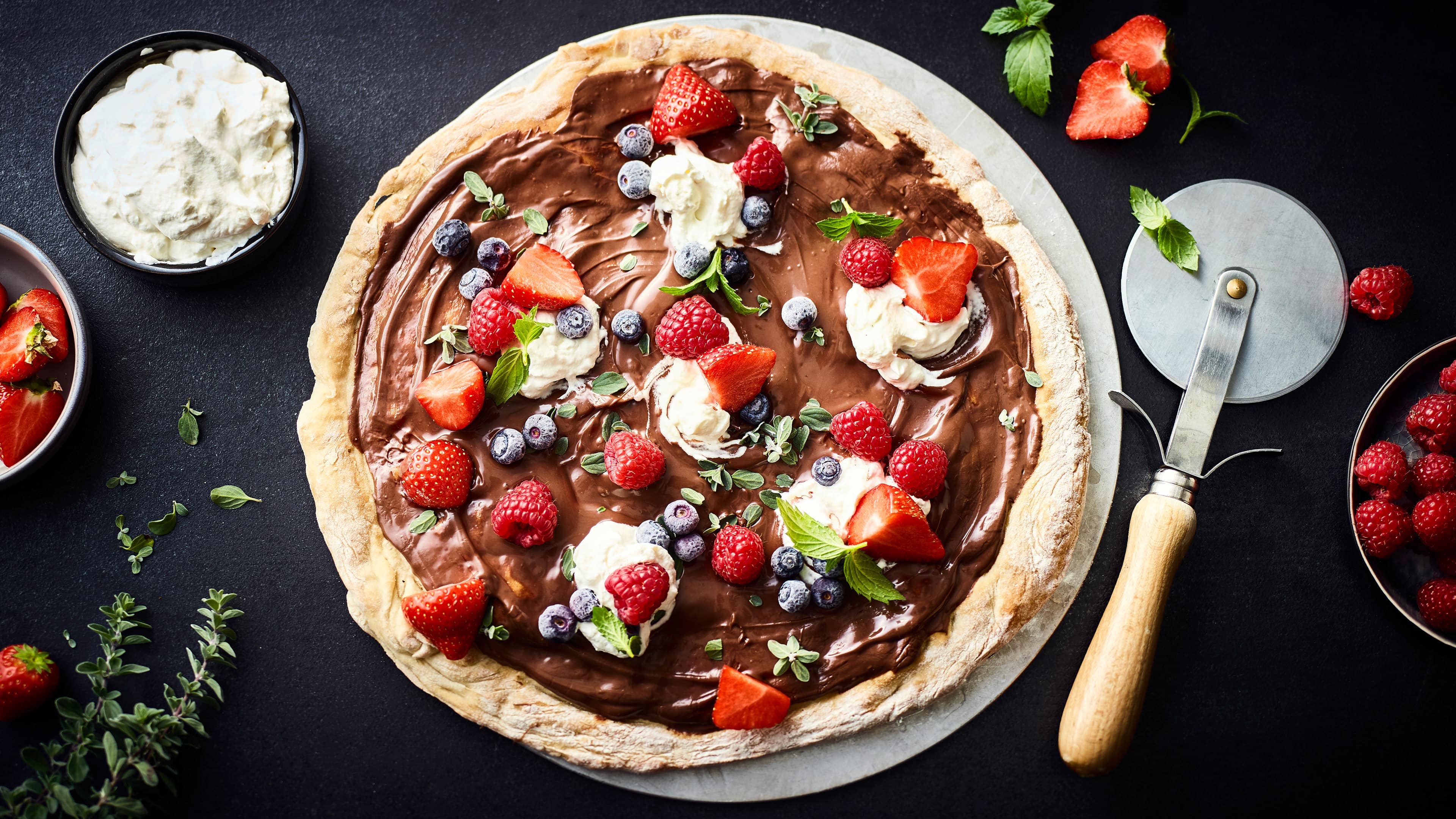 Schokoladen-Beerenpizza Pizza als Nachtisch – das geht! Mit diesem Rezept gelingt Ihnen eine sündhaft leckere Schokoladenpizza mit frischen Beeren und Minze.