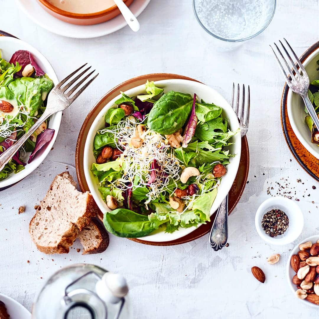 Festliche Vorspeise für Ihr Wintermenü: Probieren Sie unser Rezept für einen gemischten Salat mit gerösteten Nüssen und Orangen-Sahne-Dressing aus!