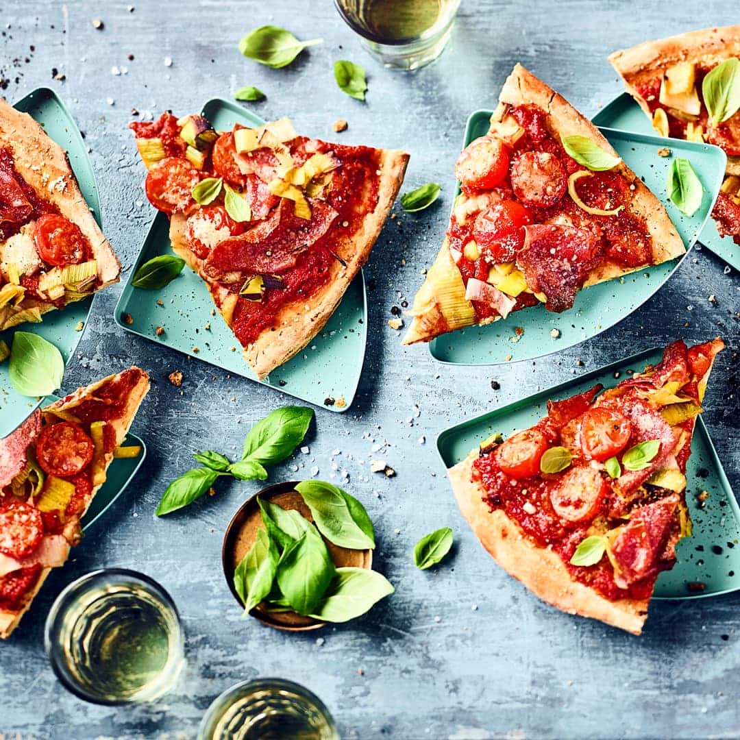 Backen Sie eine Pizza mit feinem Aufschnitt und Gemüse: Unser Rezept für Salamipizza mit frischem Lauch kommt bei Familie und Gästen gleichermaßen gut an!