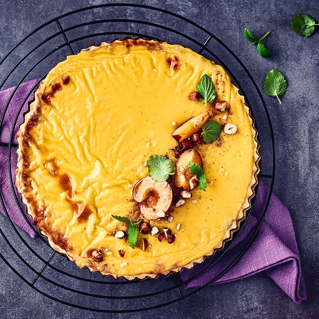 Vanillepudding und Pflaumenkompott machen diese Tarte ganz besonders schmackhaft. Mit Pflaumen, Minze und gehackten Haselnüssen garnieren.