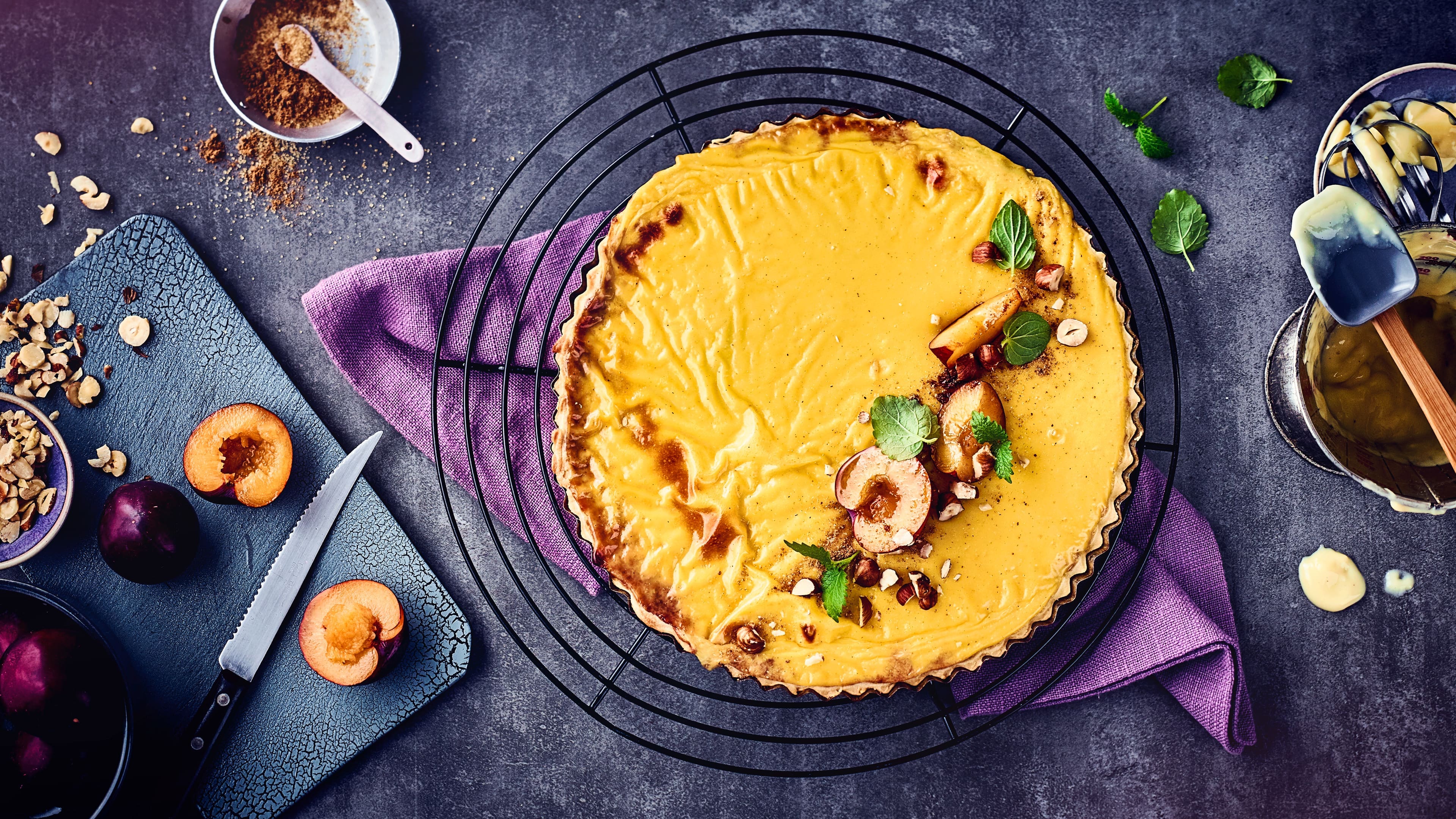 Pflaumen-Vanilletarte Vanillepudding und Pflaumenkompott machen diese Tarte ganz besonders schmackhaft. Mit Pflaumen, Minze und gehackten Haselnüssen garnieren.