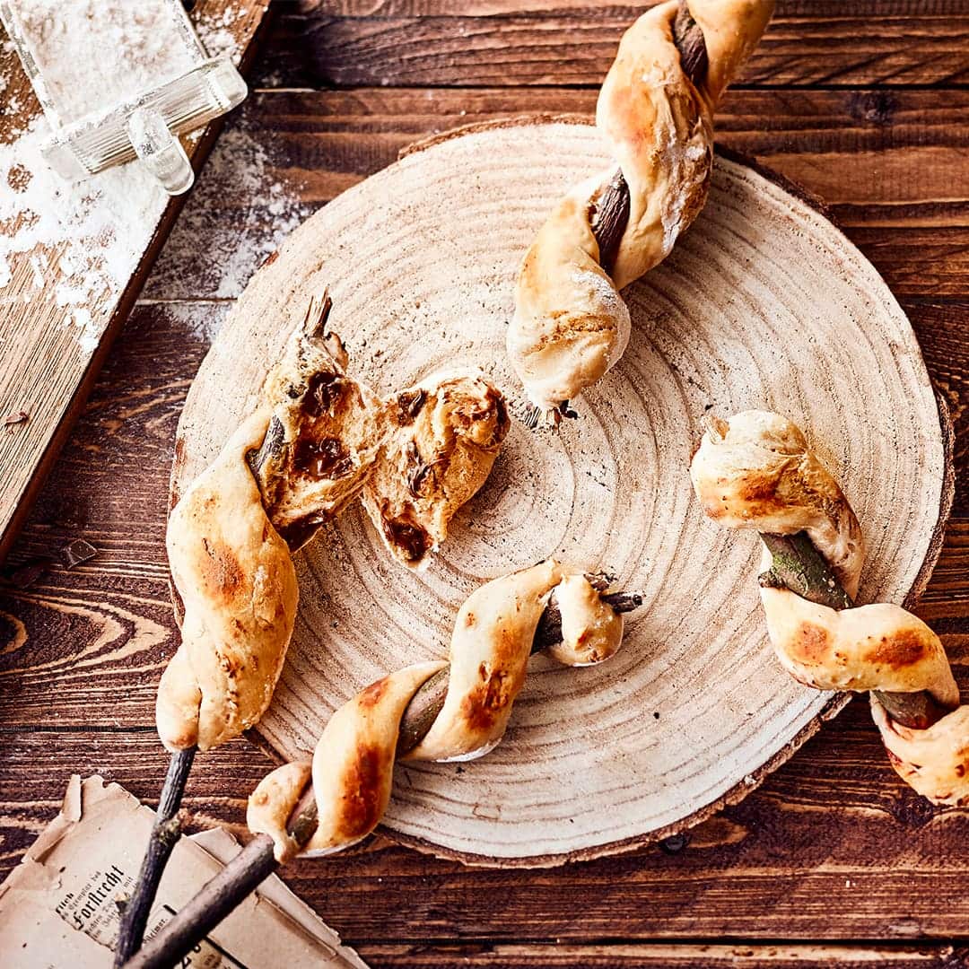 Gesellig zusammensitzen und warmes Stockbrot genießen. In unserer Version sogar mit leckeren Schokoladenstücken.