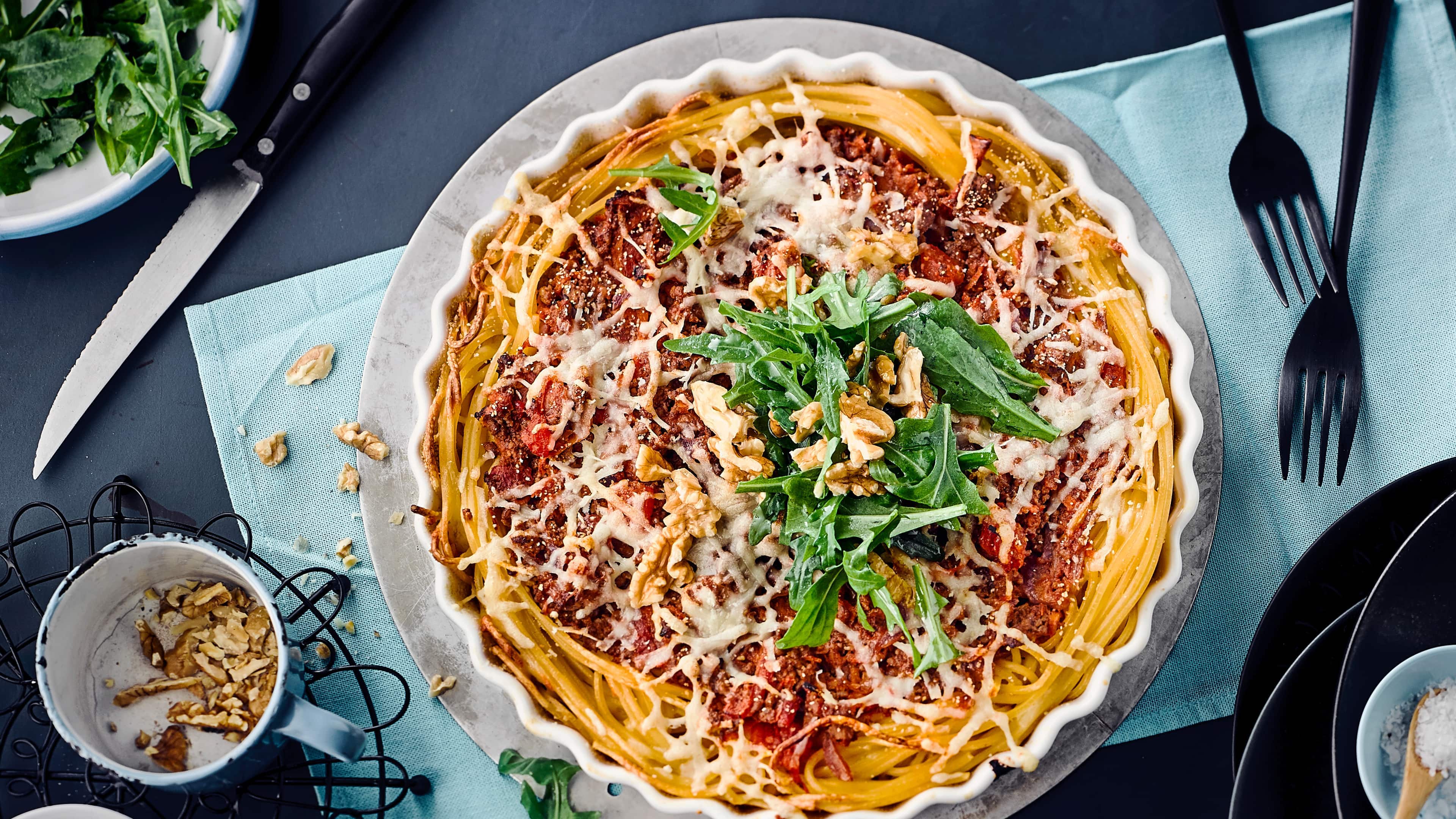 Spaghetti Tarte Pasta einmal anders: Verwöhnen Sie Ihre Familie mit unserer Spaghetti-Tarte – gefüllt mit Rinderhack, Mozzarella, Sahne und Karotten, garniert mit frischem Rucola und gehackten Walnüssen!