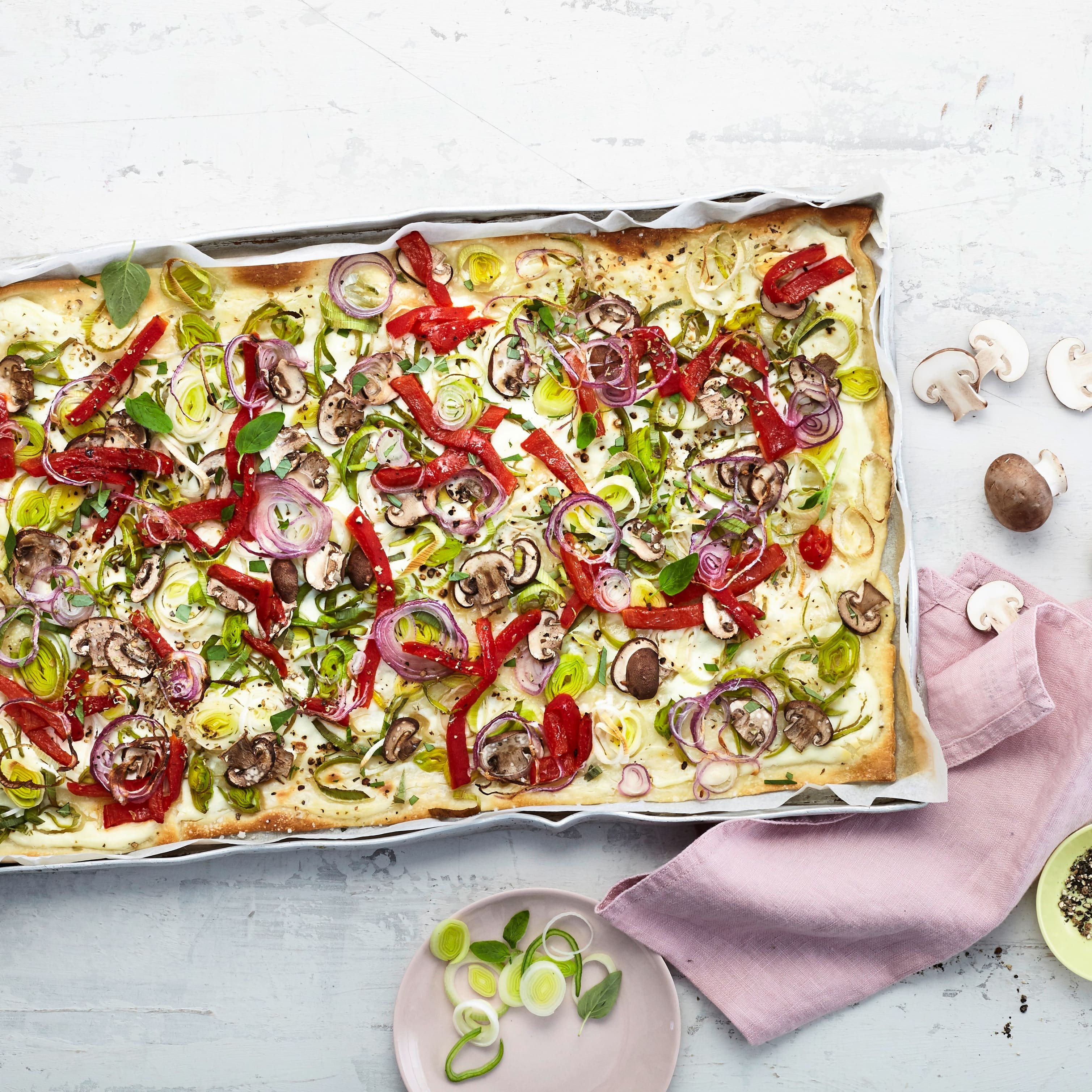 Lust auf einen schnellen Snack mit Gemüse? Probieren Sie unseren Veggie-Flammkuchen mit Röstpaprika, Porree und Champignons auf Schmand-Belag mit Ziegenfrischkäse!