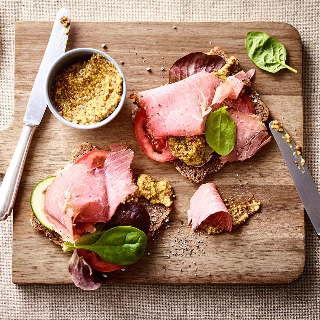 Vollkorn-Pastrami-Sandwich mit Tomate, Gurke und grobkörnigem Senf. Probieren Sie unser köstliches Vollkorn-Pastrami-Sandwich aus!
