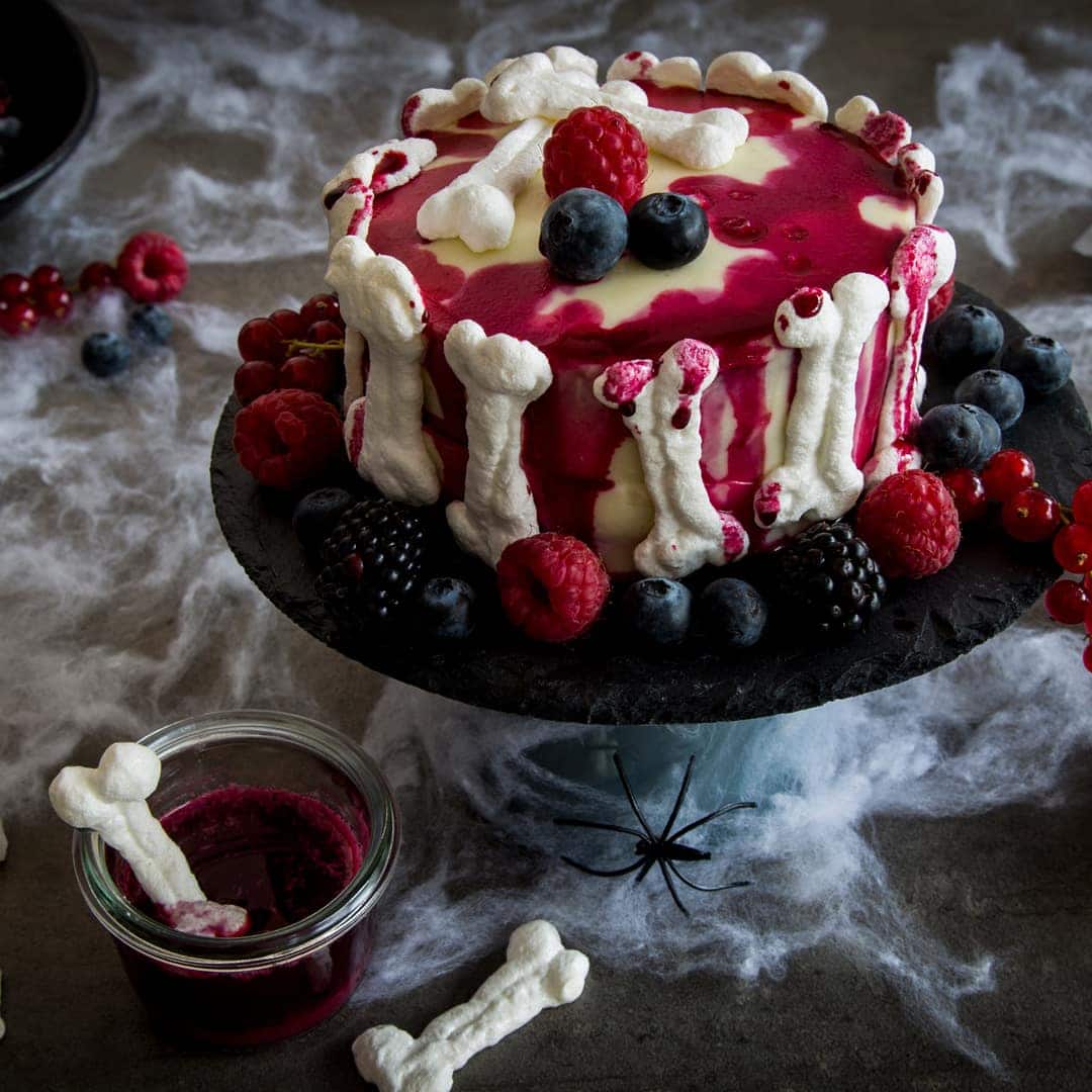 Begeistern Sie Ihre Gäste mit unserem Rezept für eine Halloween-Torte mit Beerenfüllung, Frischkäse-Frosting und Baiser-Knochen – gleich ausprobieren!