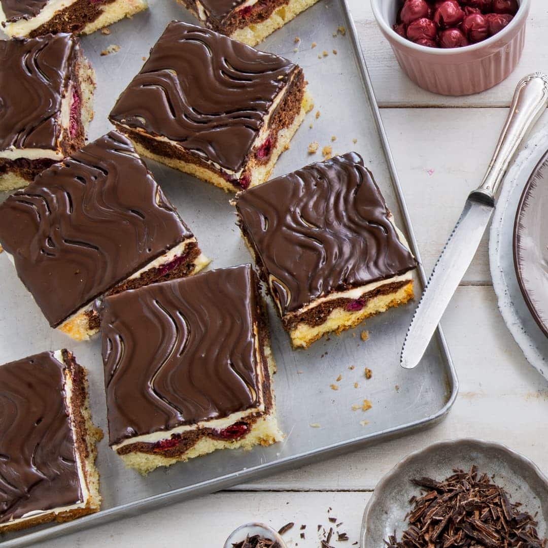 Typisches Wellenmuster auf der Schokolade, zweifarbiger Kuchenteig, fruchtige Kirschen und Buttercreme – das macht eine Donauwelle aus. Mit unserem Rezept gelingt Ihnen der Klassiker.