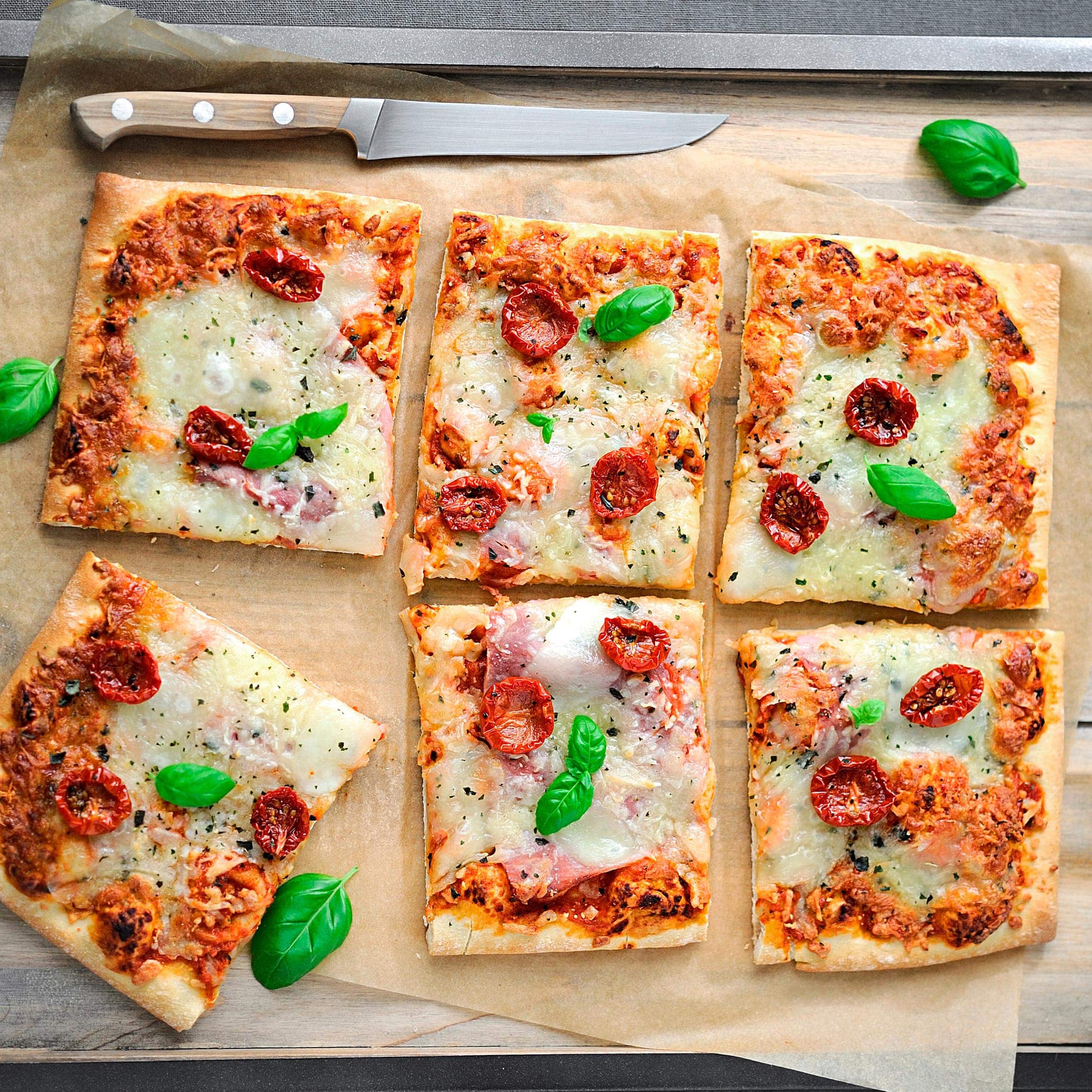 Unsere selbst gebackene vegetarische Pizza mit Tomaten, Mozzarella und Basilikum schmeckt der ganzen Familie und verspricht viel Spaß beim Belegen!