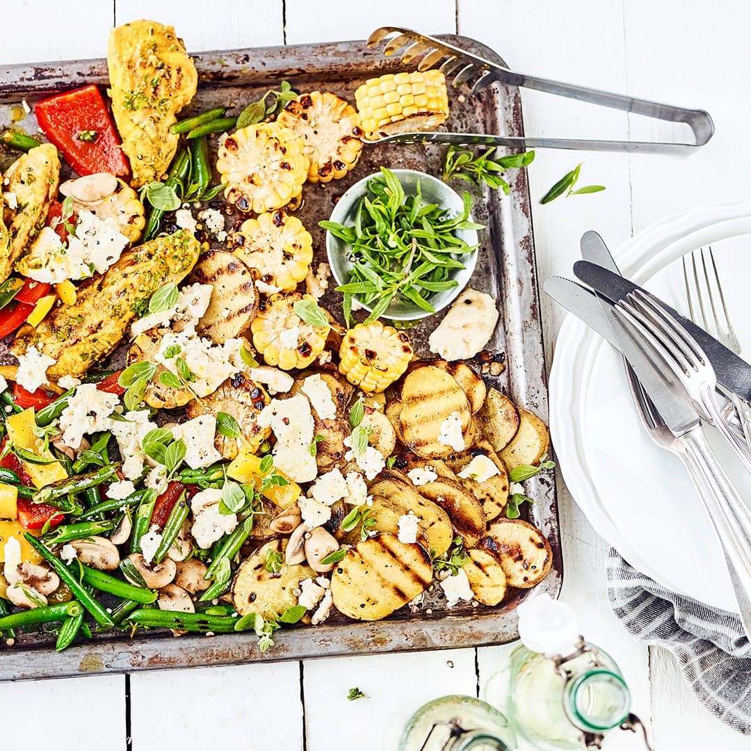 Bereiten Sie gegrillte Hähnchenschnitzel im Thymian-Curry-Gewürzmantel mit einer bunten Gemüsepfanne und Kartoffeln als Beilage zu.
