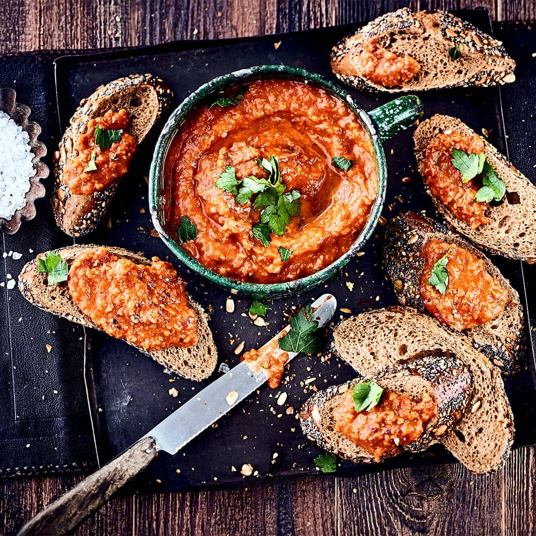 Diese rote Olivenpaste hat ihren Ursprung in Südfrankreich und schmeckt gut zu frischem Brot: Probieren Sie unsere Tapenade à la Tomate mit Knoblauch, Thymian und Sardellenfilets – pikant und lecker!