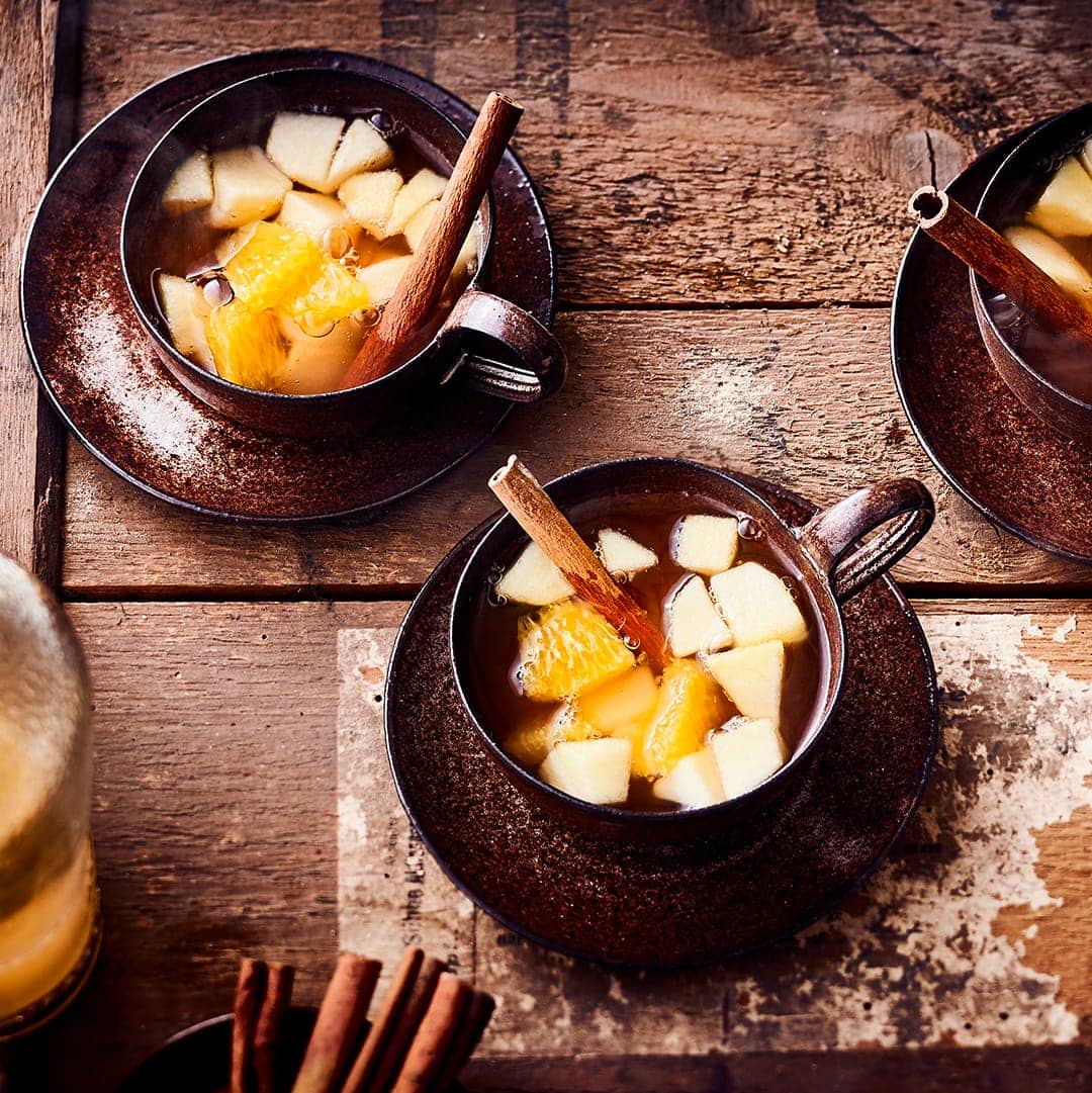 Perfekt für die kalte Jahreszeit -  Unser Rezept für Heiße Apfelbowle aromatisiert mit Calvados, Gewürzen und fruchtigen Apfel- und Orangenwürfel.