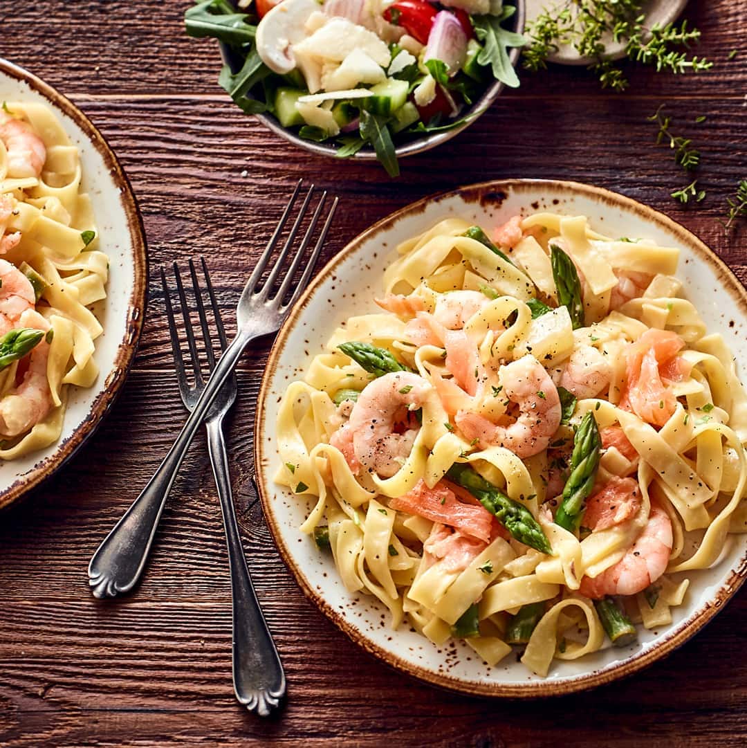 Leckeres Pastagericht: Probieren Sie unsere Bandnudeln mit grünem Spargel, geräuchertem Lachs und Scampis an Gurkensalat mit Balsamico-Senf-Dressing!