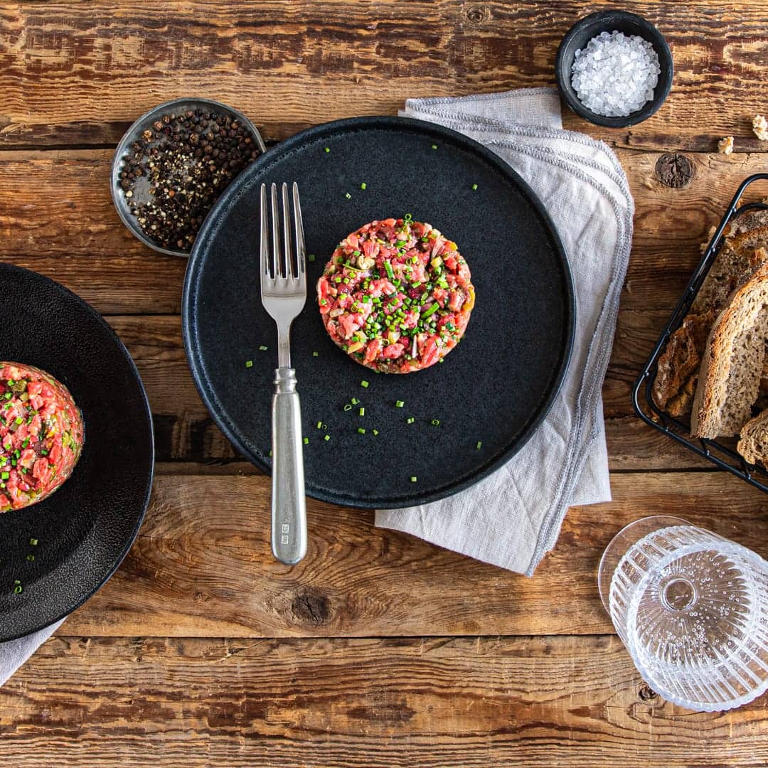Selbstgemachtes Rindertatar aus Rinderfilet, Schnittlauch, Kapern, Schalotten und Cornichons – am besten serviert auf frischem Bauernbrot.