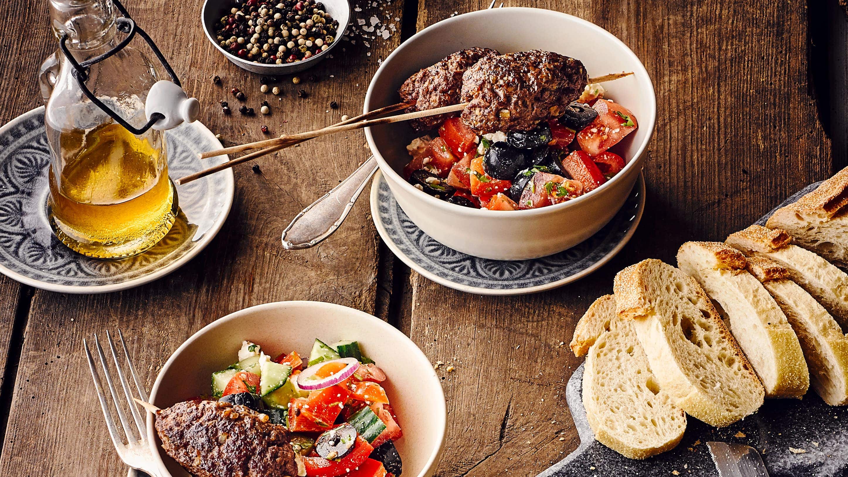 Cevapcici Cevapcici mit griechischem Salat und Weißbrot angerichtet