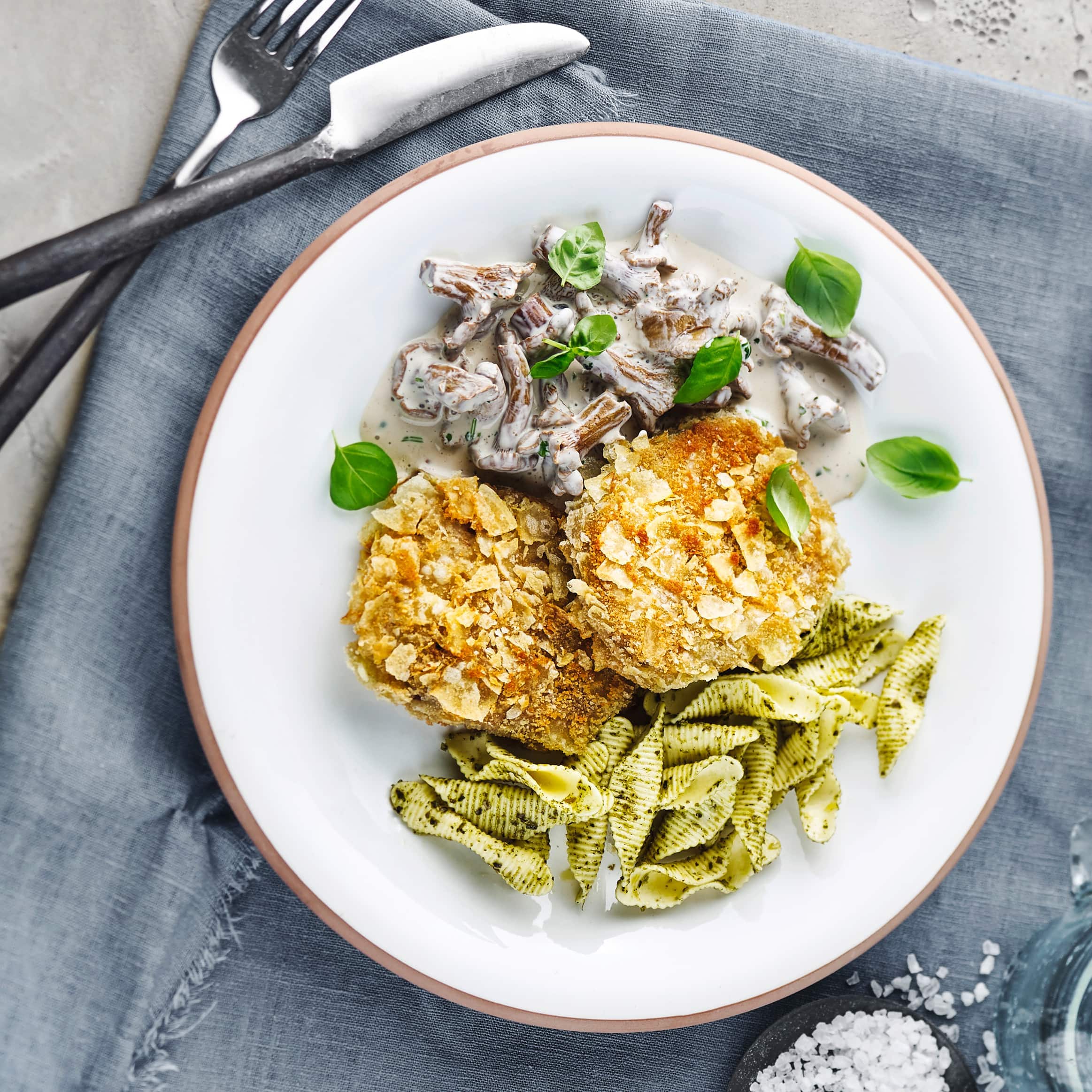 Ein echter Hingucker! Unser Rezept für Veganes Knusperschnitzel aus Seitan - kombiniert mit einer Pilzcreme aus Weißwein und Pesto-Pasta.