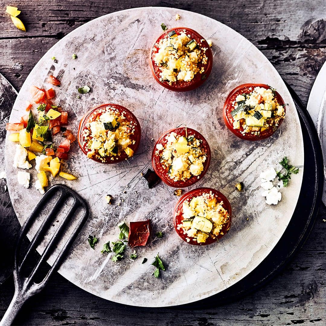 Grillen Sie in nur 30 Minuten vegetarisch gefüllte Tomaten mit Couscous und würzigem Fetakäse – mit Kreuzkümmel und frisch gepresster Zitrone abgeschmeckt.