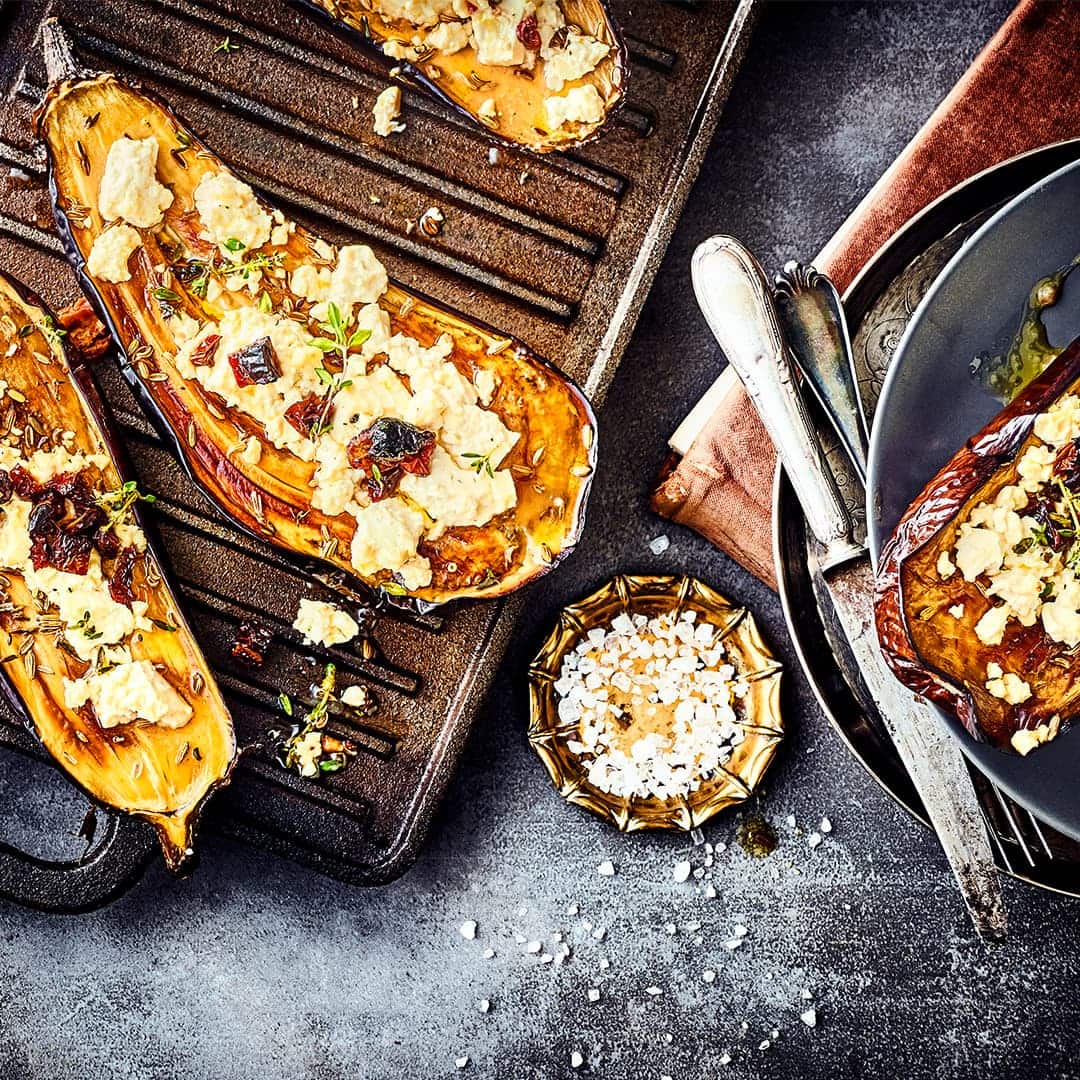 Unser Rezept für gefüllte Aubergine mit Ziegenkäse, Knoblauch-Tomaten-Öl und frischen Kräutern ist vegetarisch und lecker – gleich ausprobieren!