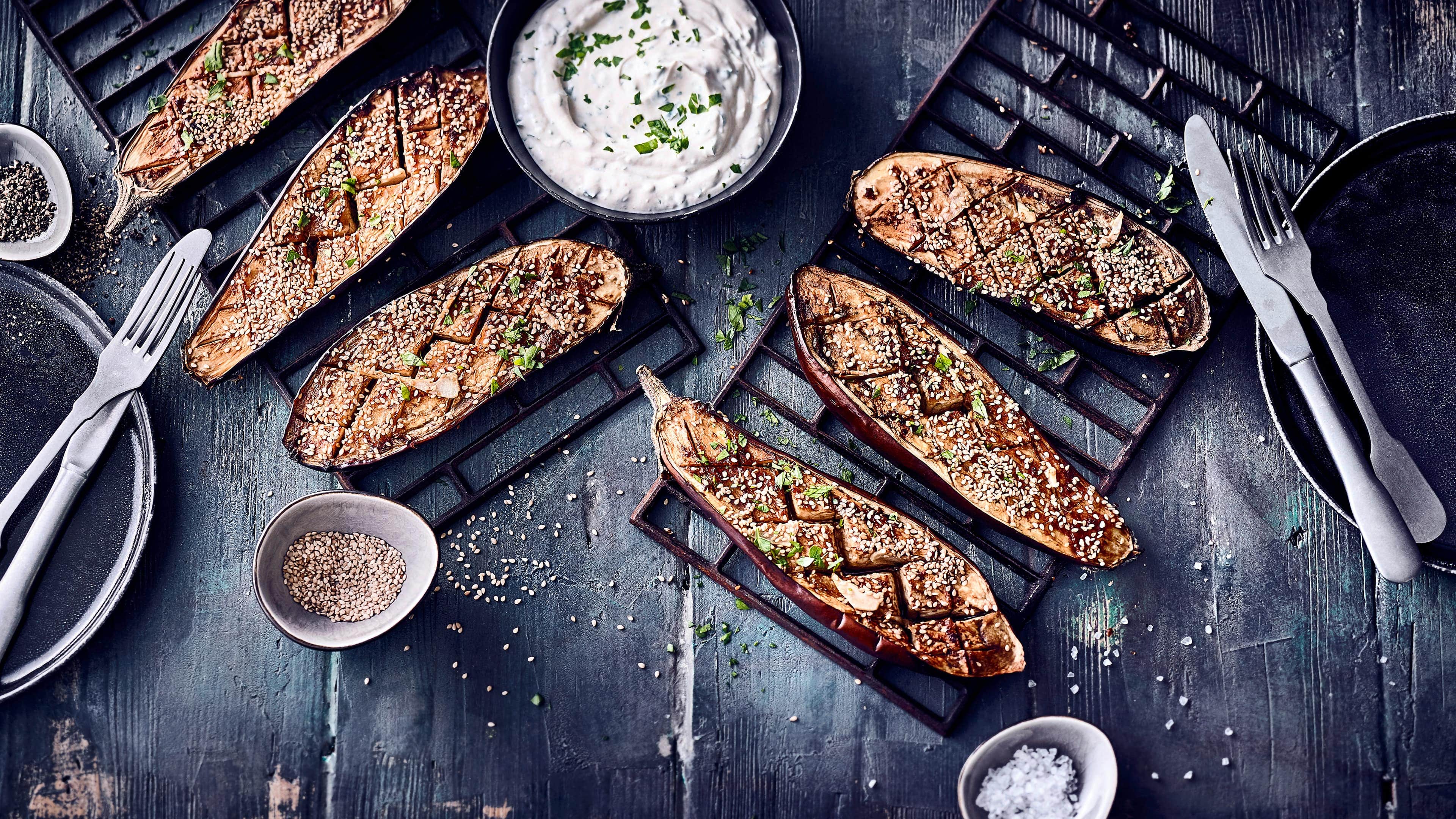 Gebackene Auberginen Leicht orientalisch gewürzt schmecken unsere gebackenen Auberginen herrlich lecker und werden mit selbstgemachter Joghurt-Soße und Granatapfelkernen serviert.