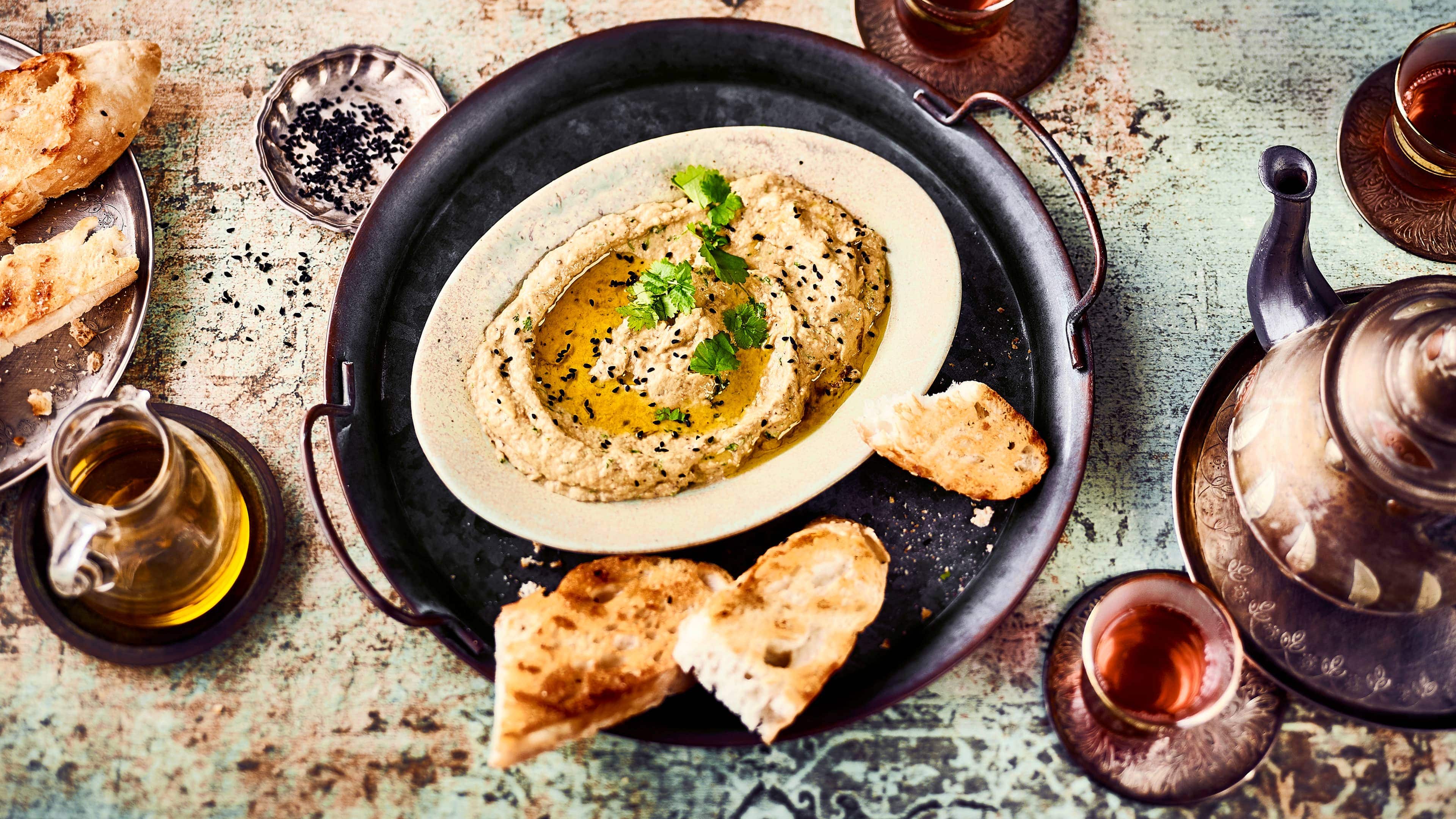 Baba Ganoush Auch bekannt als Auberginencreme oder Auberginenpaste ist Baba Ganoush ein Rezept der orientalischen Küche aus Auberginen, Knoblauch, Koriander und Tahin.
