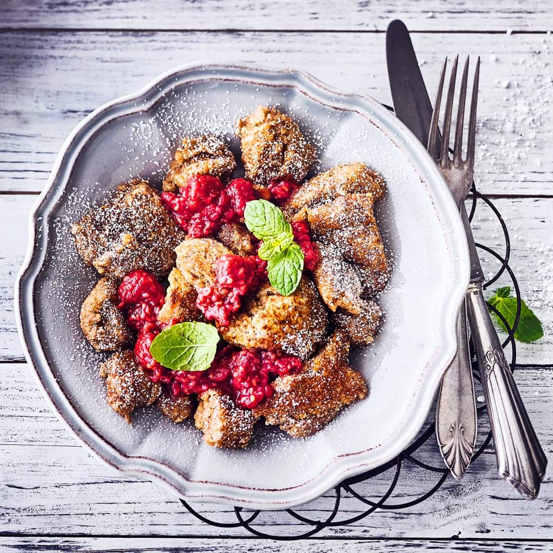 Köstlicher veganer Kaiserschmarrn mit Puderzucker und heißem selbstgemachtem Himbeerkompott ist nicht nur ein kleines Highlight des Tages.